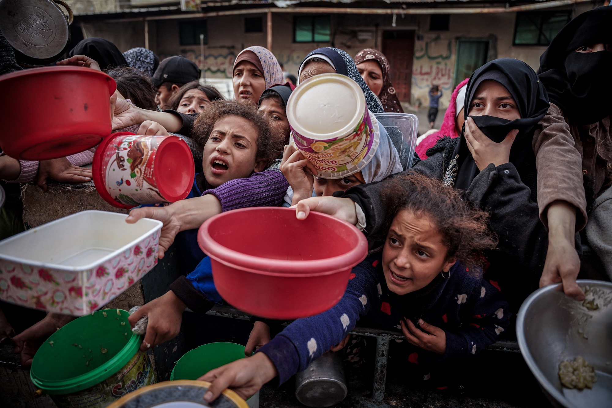 Palestinians wait to collect food at a donation point in a refugee camp in Rafah, southern Gaza, on December 23, 2023.