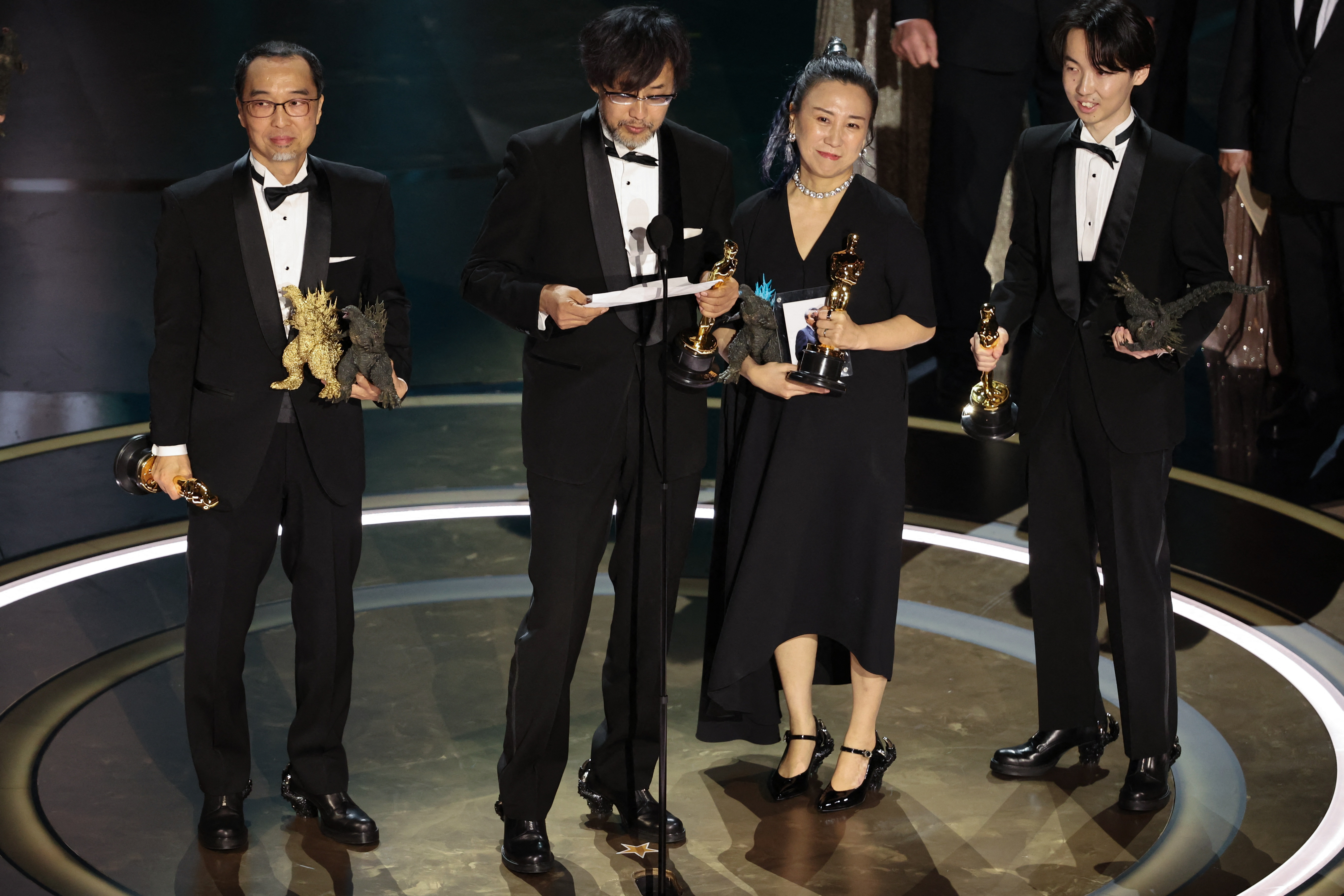 Takashi Yamazaki, second from left, accepts the award for best visual effects for "Godzilla Minus One.” 