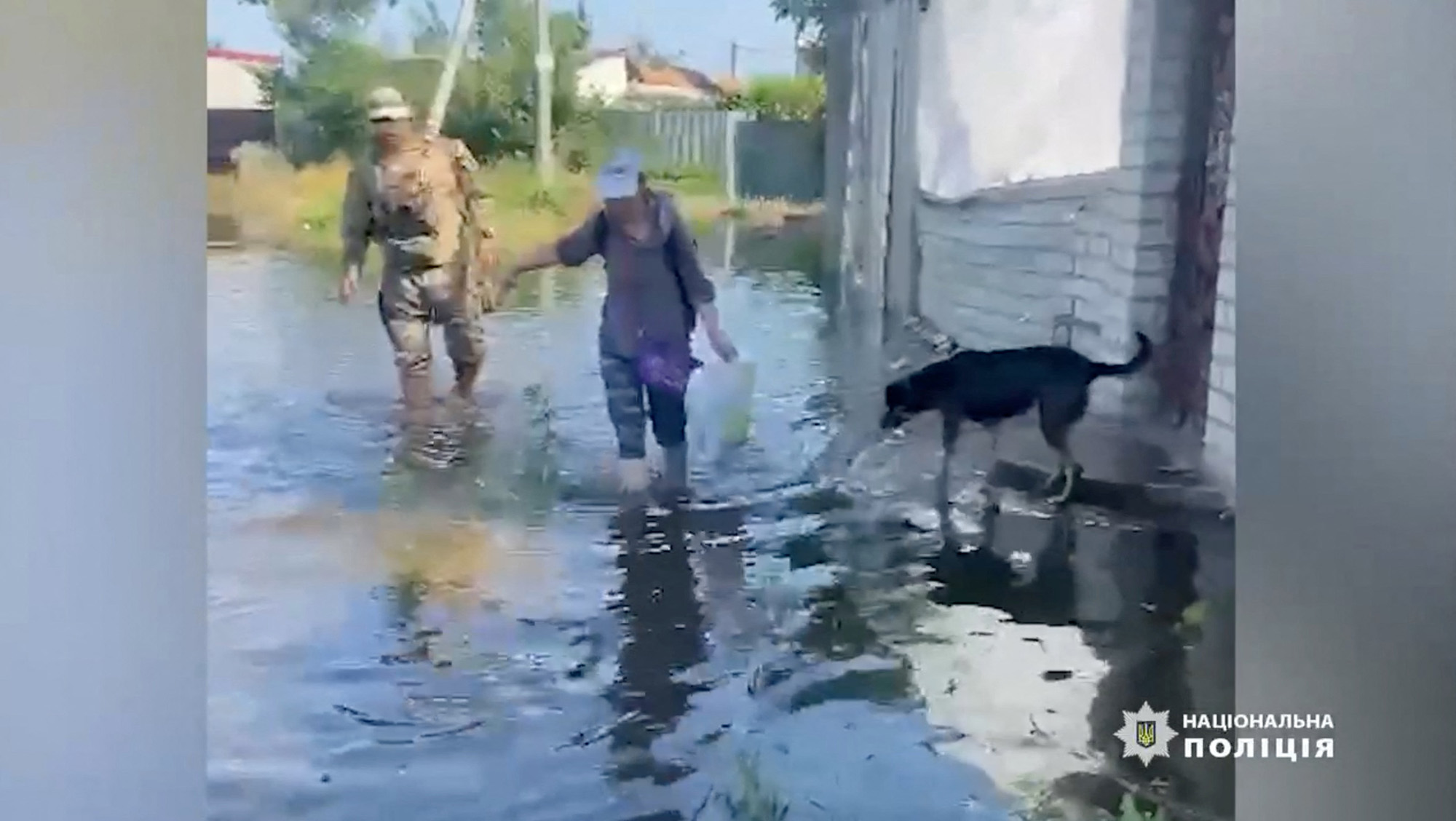 A person wades through floodwaters as police officers conduct patrols and help citizens evacuate to safe places following floods in Kherson region, Ukraine, on June 6.