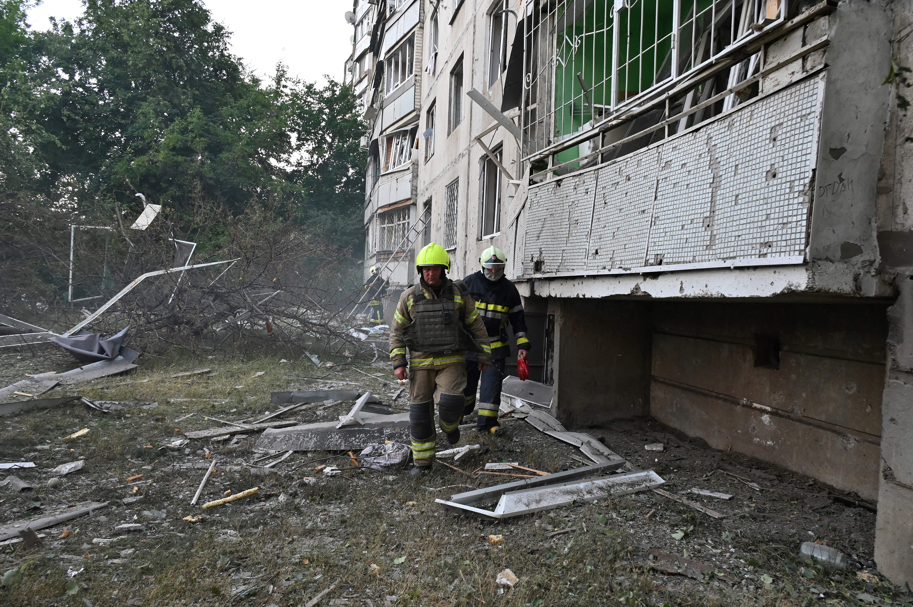 Firefighters walk by a partialy destroyed building after shelling of multiple launch rocket systems in Kharkiv on July 7. At least three civilians were killed and five injured.