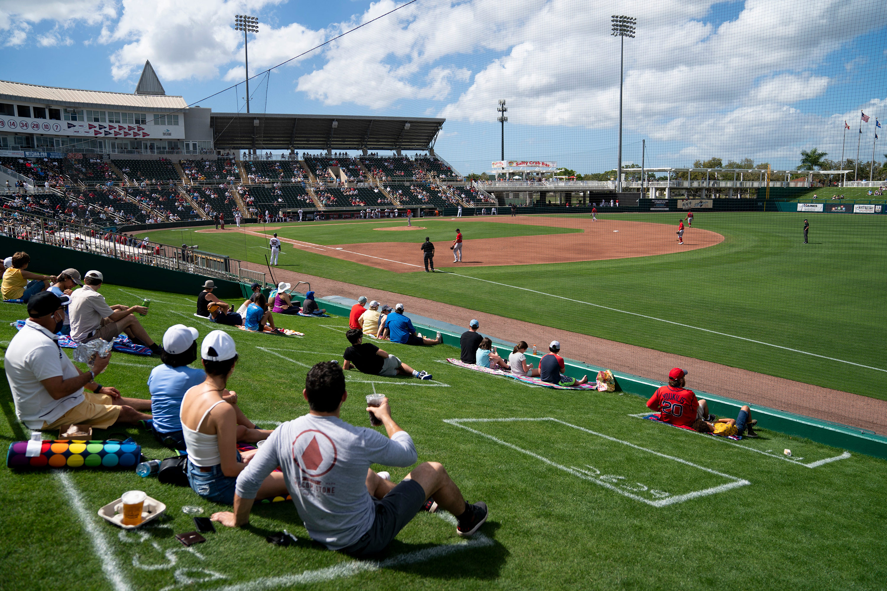 Fanii stau în dreptunghiuri destinate să încurajeze distanțarea socială în timpul primului meci de antrenament de primăvară dintre Minnesota Twins și Boston Red Sox din Fort Myers, Florida, pe 28 februarie.