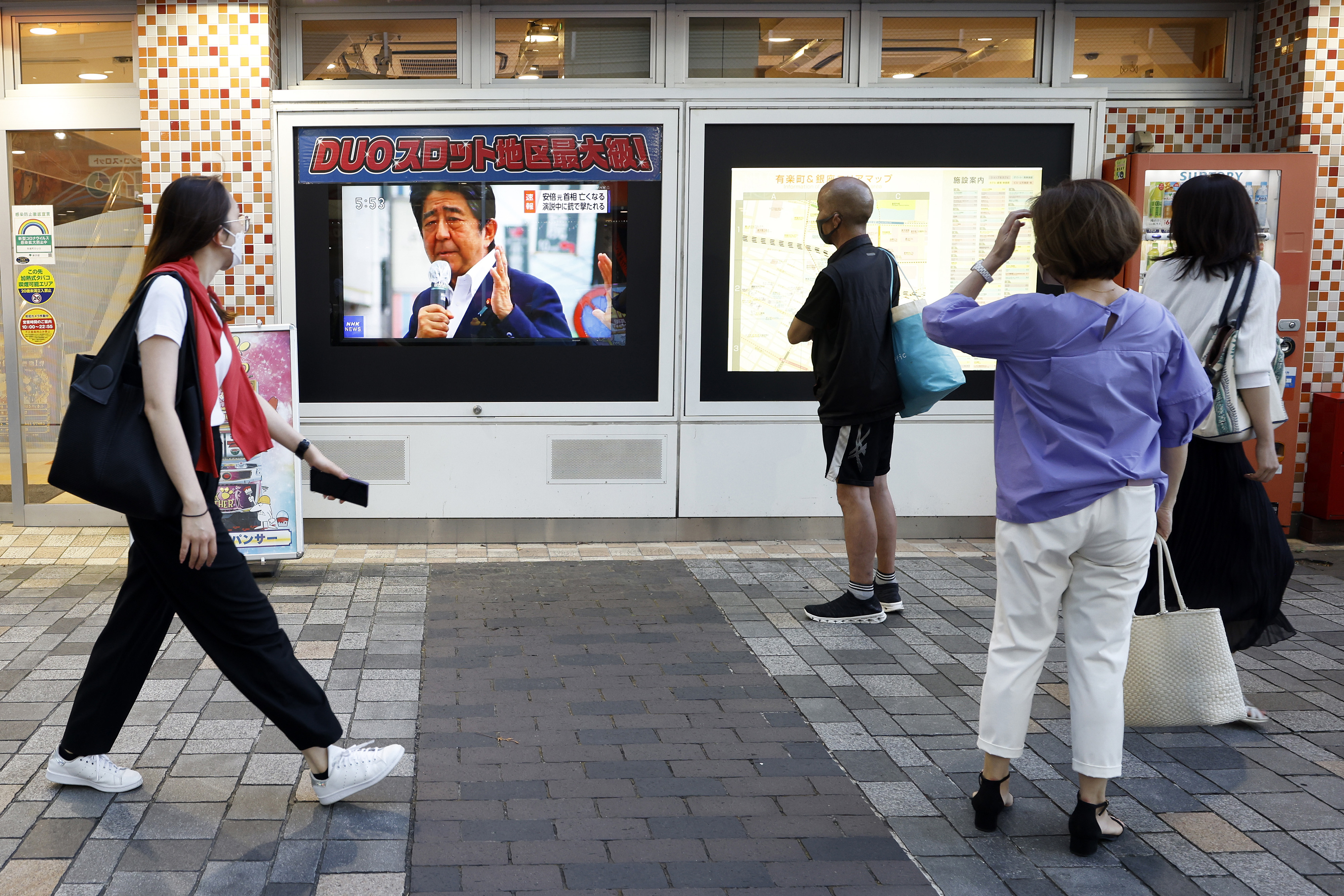 Pedestrians watch a news broadcast about the assassination of former Japanese Prime Minister Shinzo Abe, in Tokyo, on July 8. 