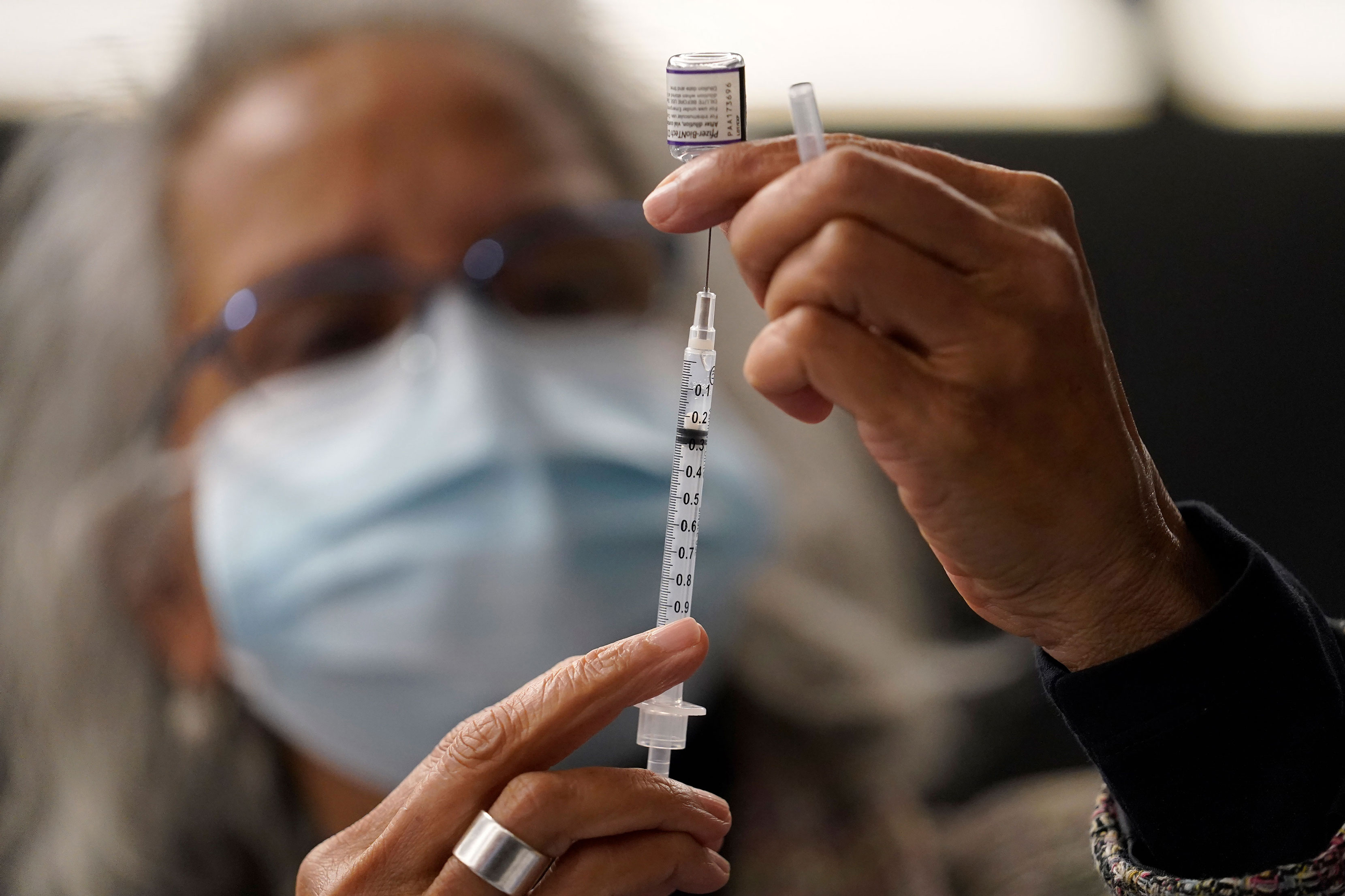 Dr. Manjul Shukla transfers Pfizer COVID-19 vaccine into a syringe on Thursday, Dec. 2, 2021, at a mobile vaccination clinic in Worcester, Massachusetts.