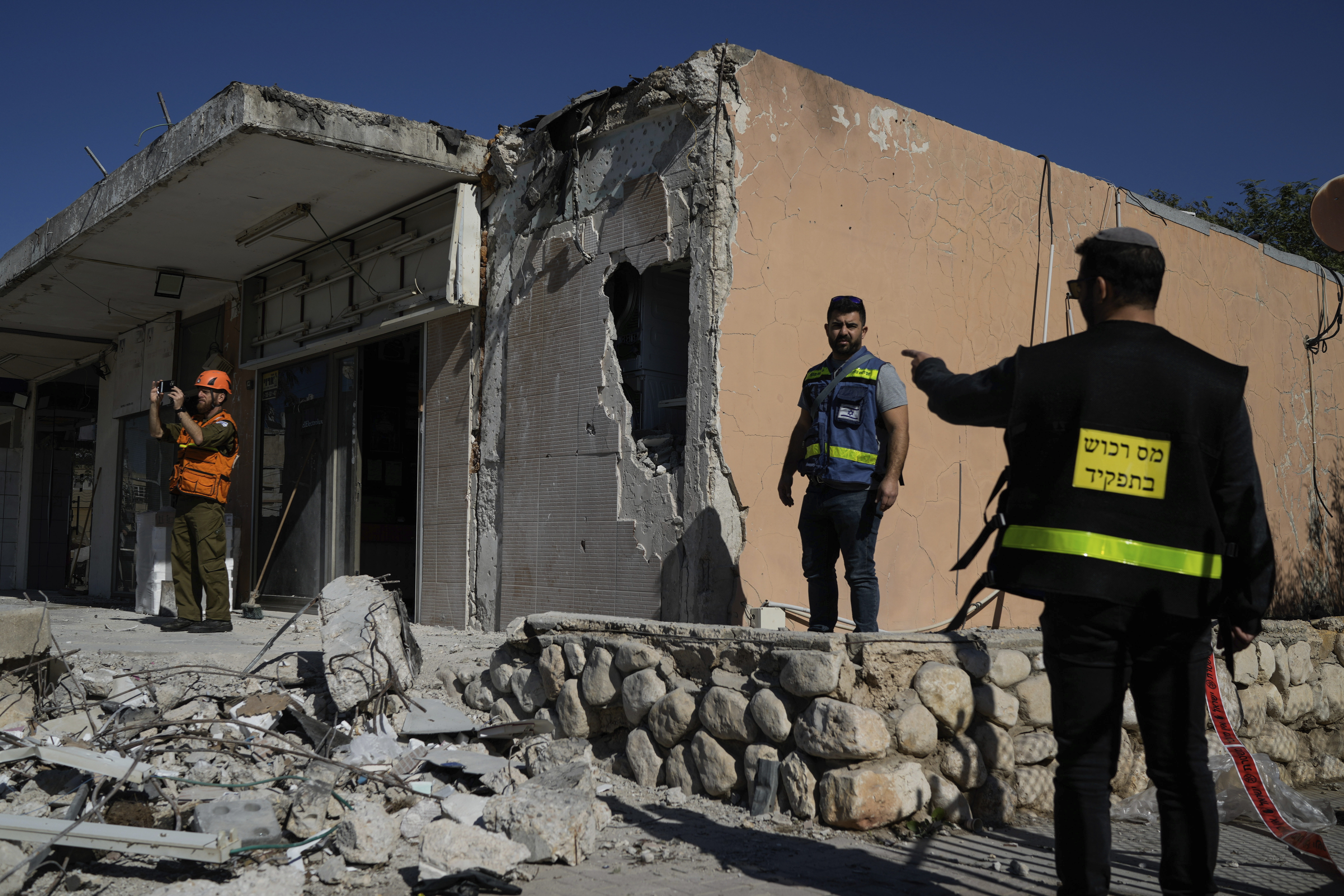 Israeli security forces and property tax officials examine a damaged store in Netivot, Israel, after it was hit by a rocket fired from Gaza on January 16.