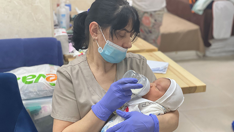 A nanny at the surrogacy clinic feeds a newborn baby who is waiting to be picked up by its new parents.