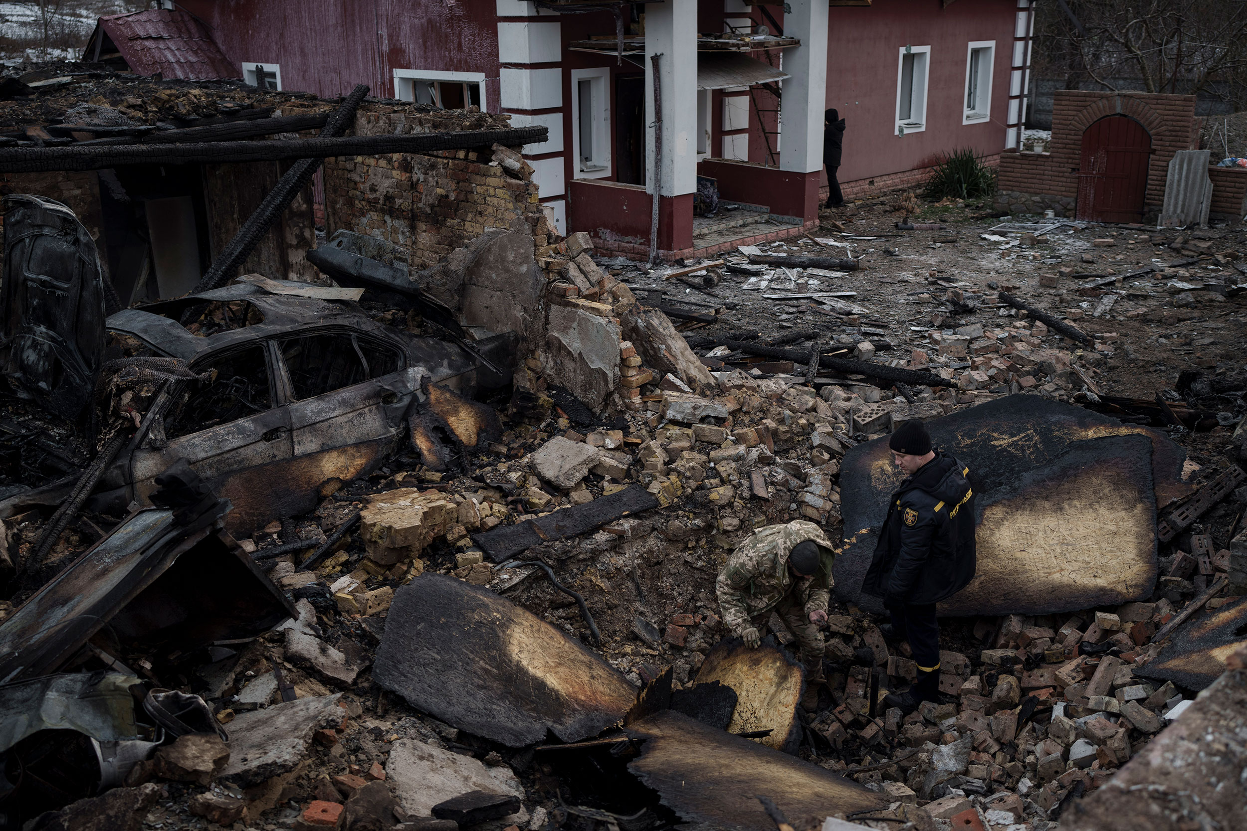 A Ukrainian firefighter and serviceman inspect damage caused by a Russian drone outside the home of Ivan and Olha Kobzarenko.