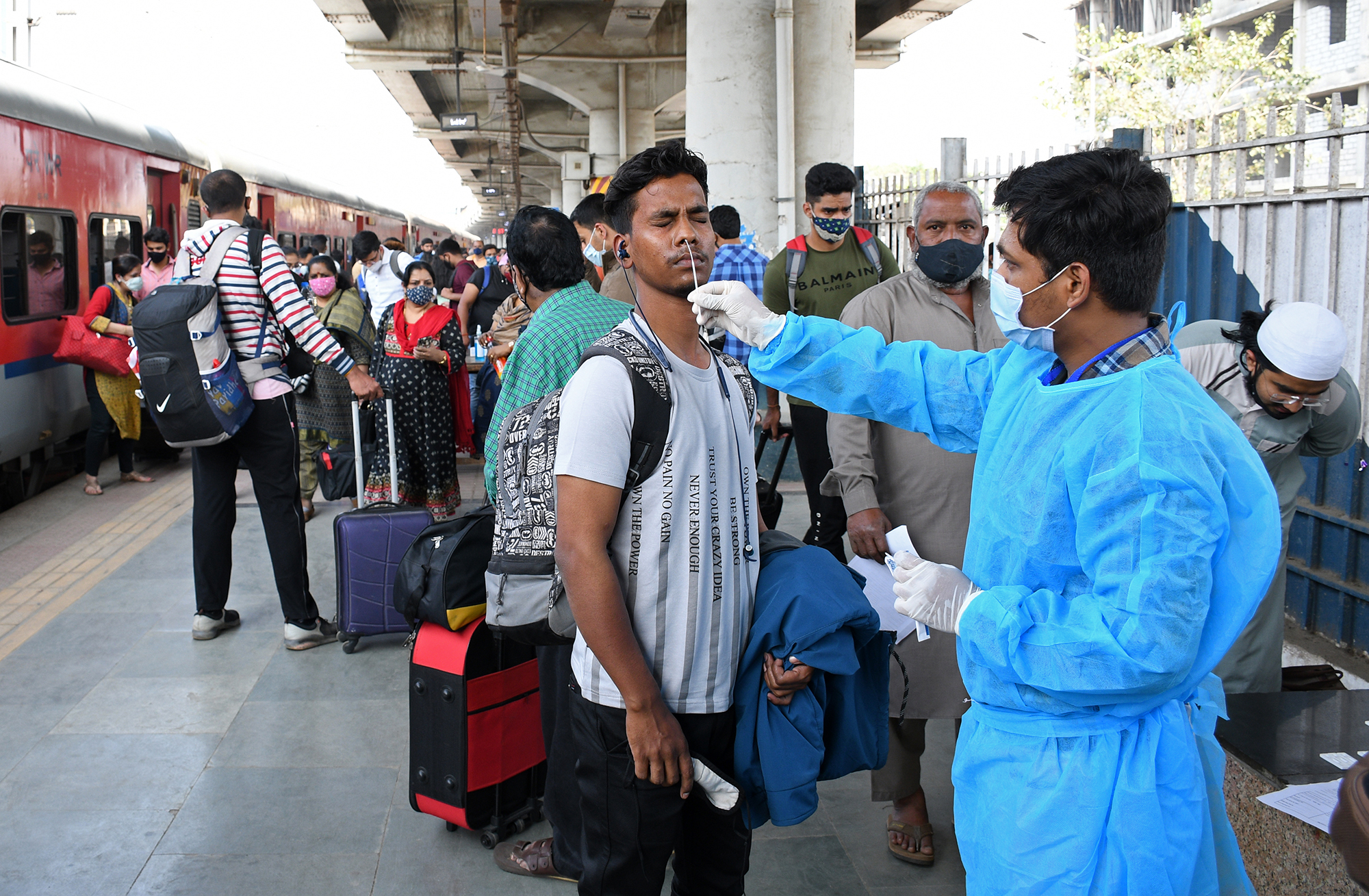 MUMBAI, INDIA - 2021/12/31: A healthcare worker collects a nasal swab sample from a man at Dadar railway station in Mumbai, India on 31 December 2021. Due to rise in Omicron cases in the city, passengers arriving from outstation who are not fully vaccinated or carrying a negative RT PCR report along with them have to undergo nasal swab testing at the railway station before they are allowed to proceed to their respective destination. 