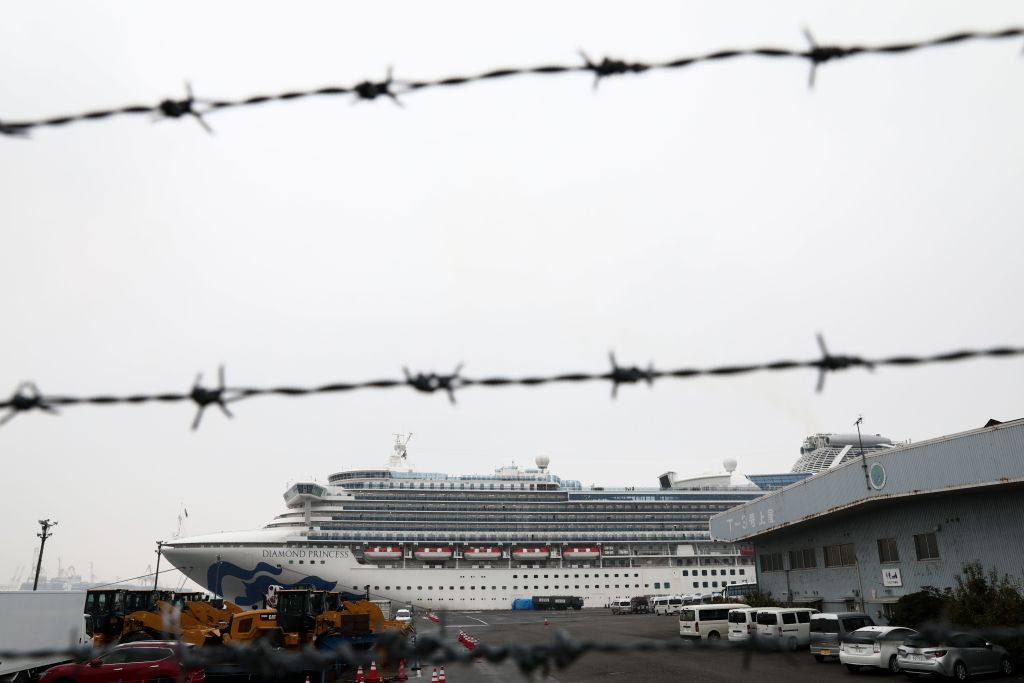 The Diamond Princess cruise ship, which has thousands of quarantined onboard due to fears of the new COVID-19 coronavirus, is seen through a fence at the Daikoku Pier Cruise Terminal in Yokohama port on February 16, 2020. 