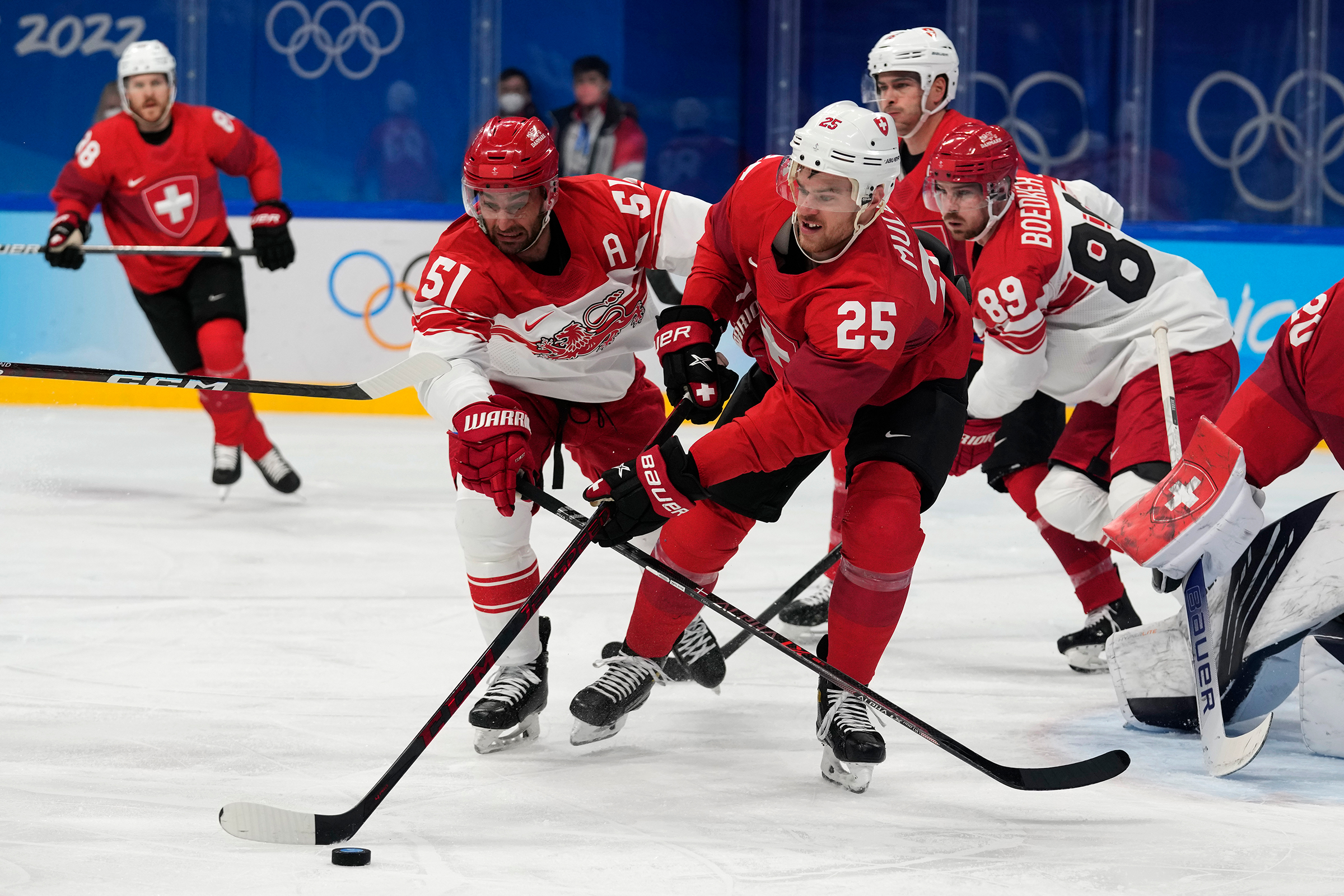 Switzerland's Mirco Muller skates with the "biscuit" away from Denmark's Frans Nielsen during a preliminary round men's hockey game on Saturday, February 12.