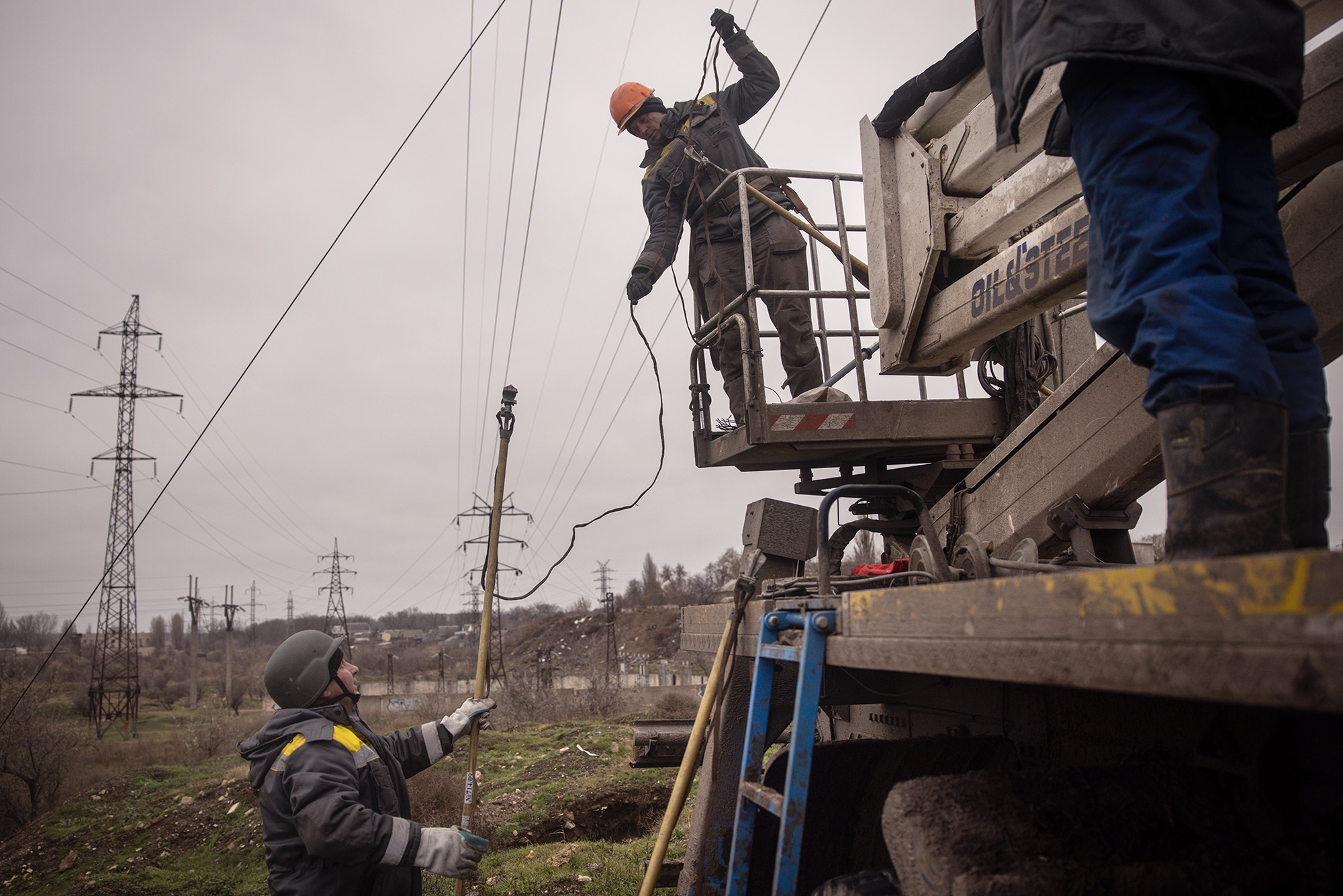Electricity workers wearing bulletproof vests and helmets work to fix a destroyed high voltage power line on December 1, in Kherson, Ukraine. 