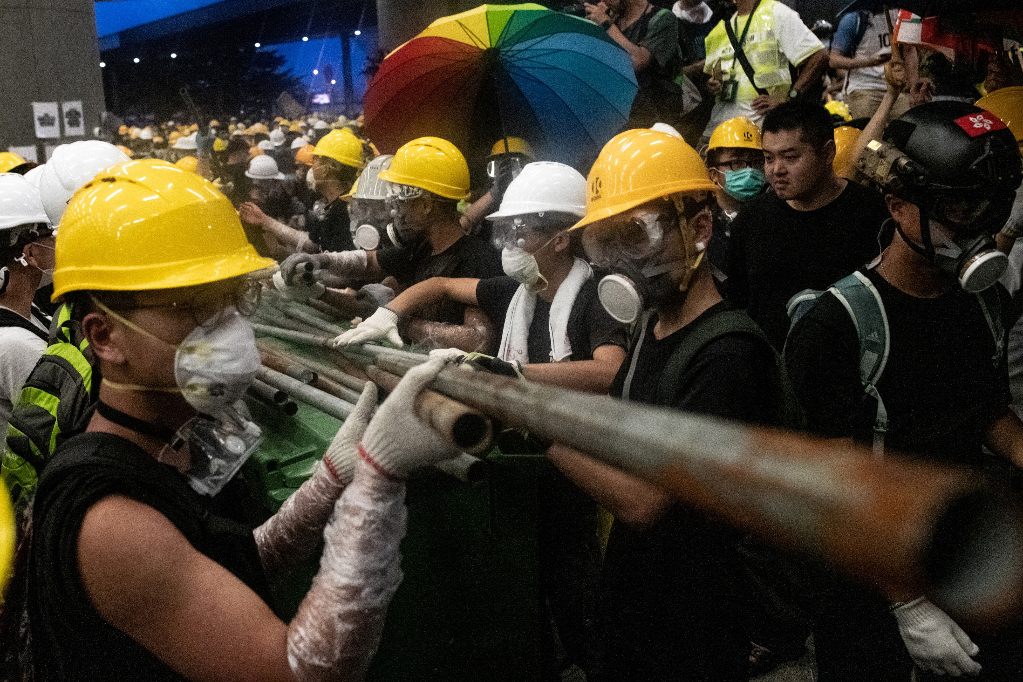 Protesters use metal rods to smash glass doors and windows of the government headquarters in Hong Kong on July 1.