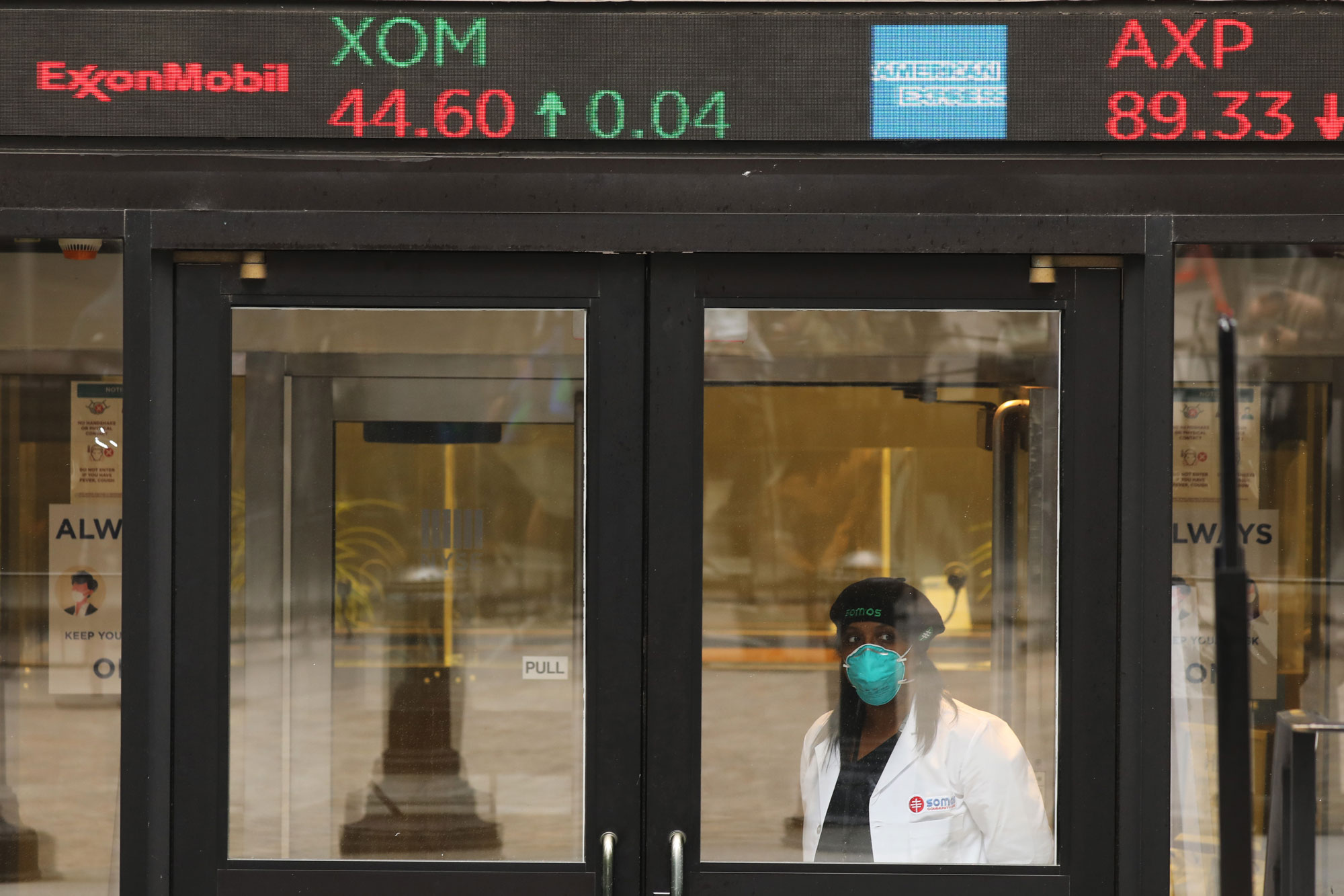 A medical worker stands at the entrance to the New York Stock Exchange on the first day that traders are allowed back onto the historic floor of the exchange on May 26 in New York City. 