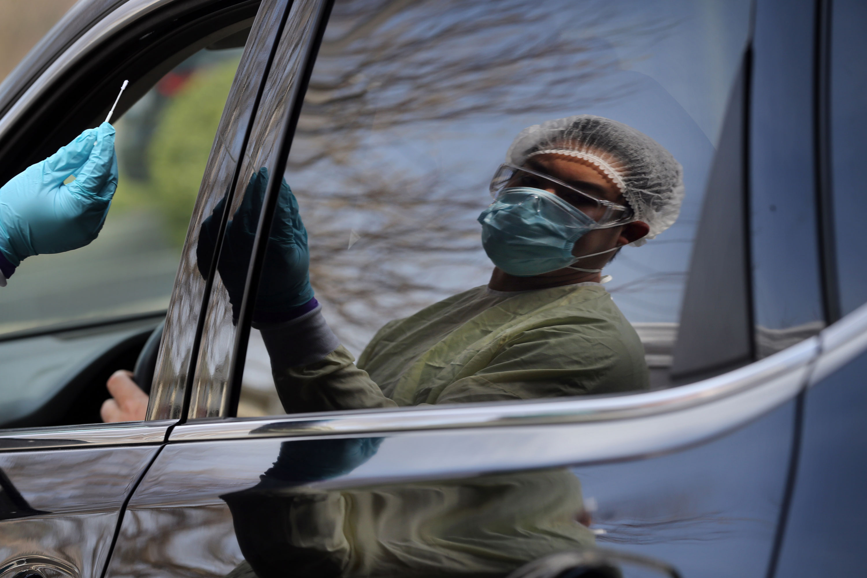 Adrian Santiago takes swabs a patient at the drive-through testing site at Beth Israel Deaconess HealthCare in Chelsea, MA on April 29.