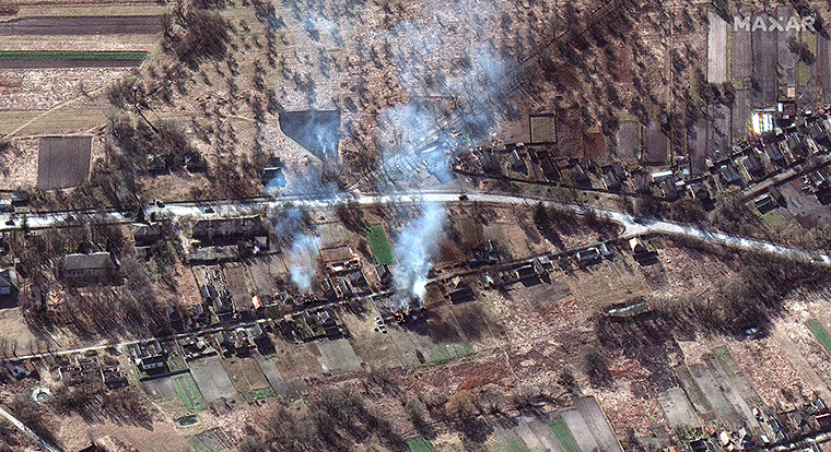 Along with part of the convoy, smoke can be seen rising from what appears to be burning homes, northwest of Invankiv, Ukraine.