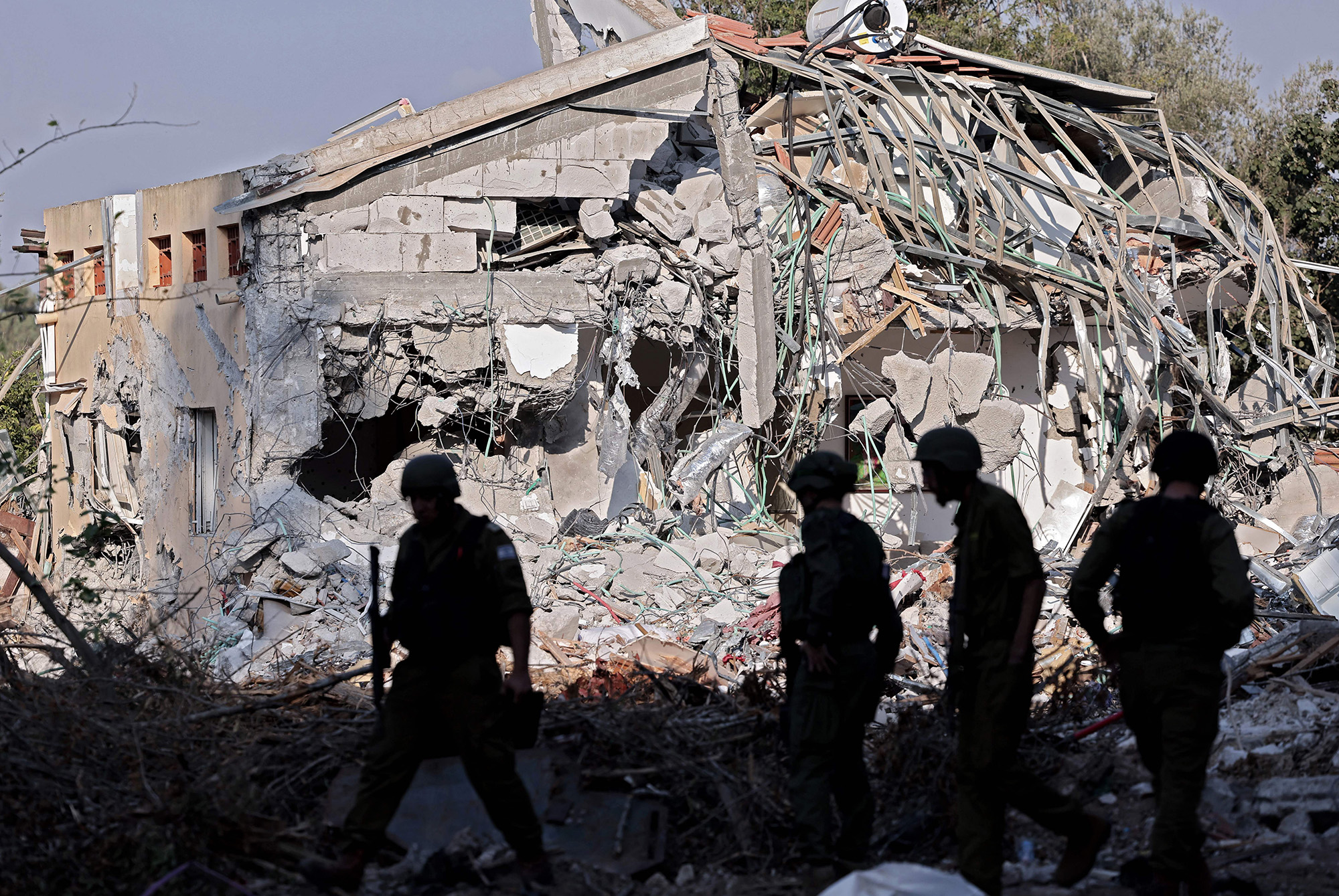 Israeli soldiers walk past a house destroyed in the October 7 attack on kibbutz Beeri, Israel, near the border with Gaza, on October 14.