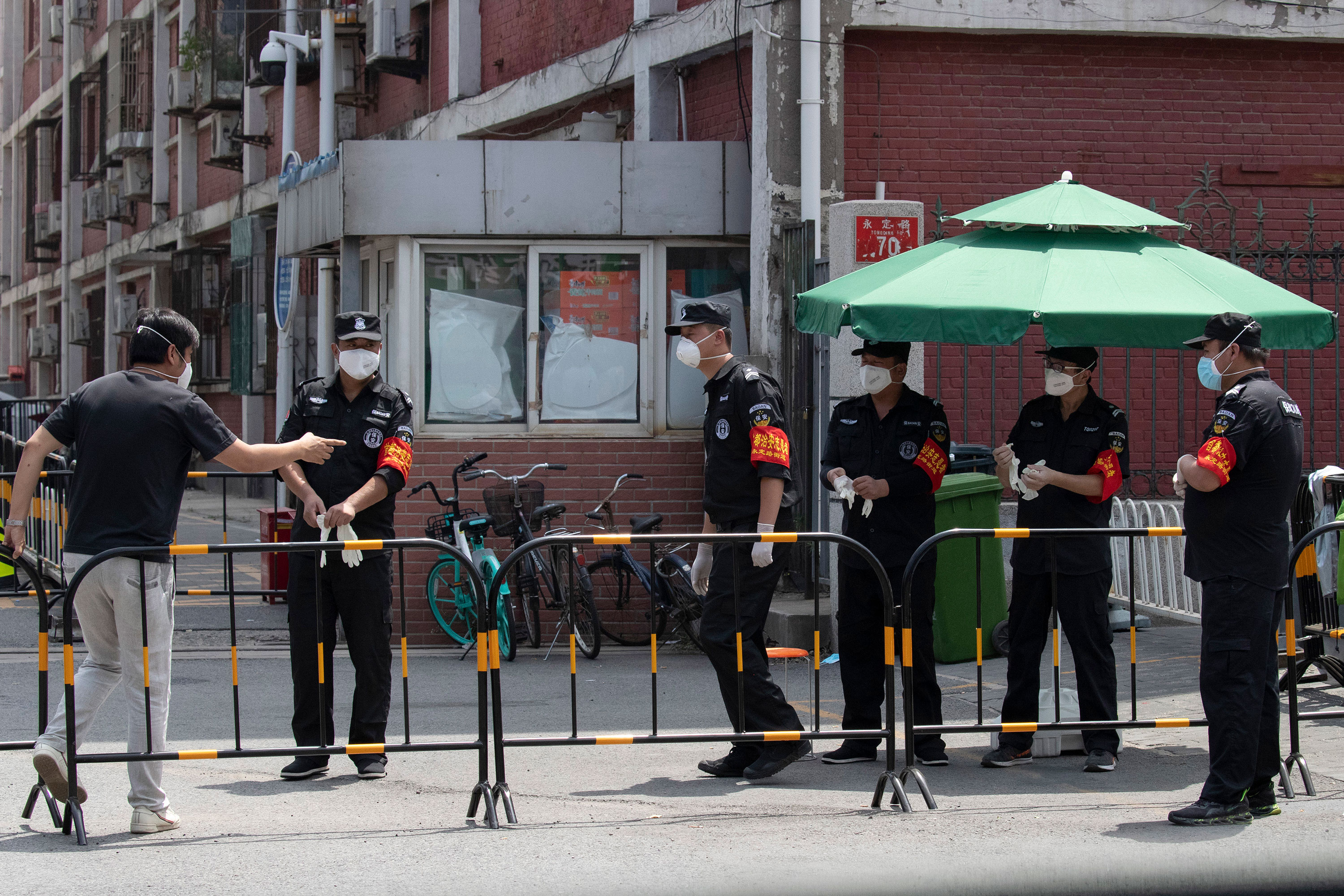 Security guards monitor a neighborhood under lockdown on June 16 in Beijing.