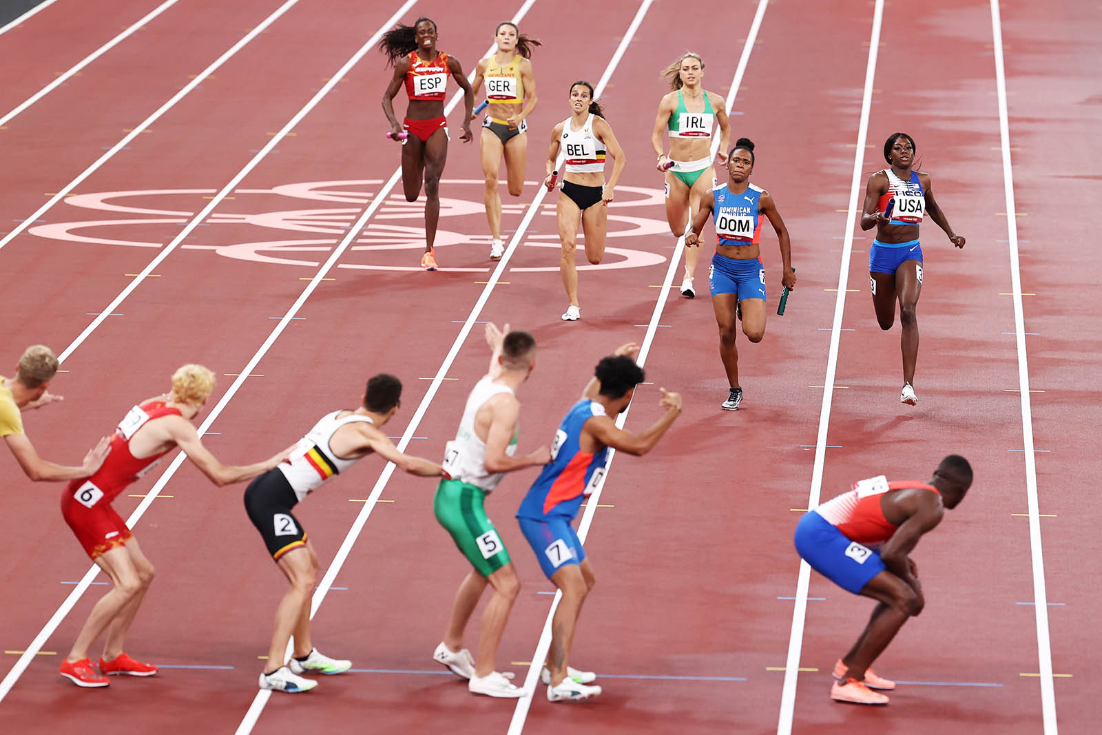 Competitors race to hand off their batons during the first round of the 4x400m mixed team relay on Friday.  