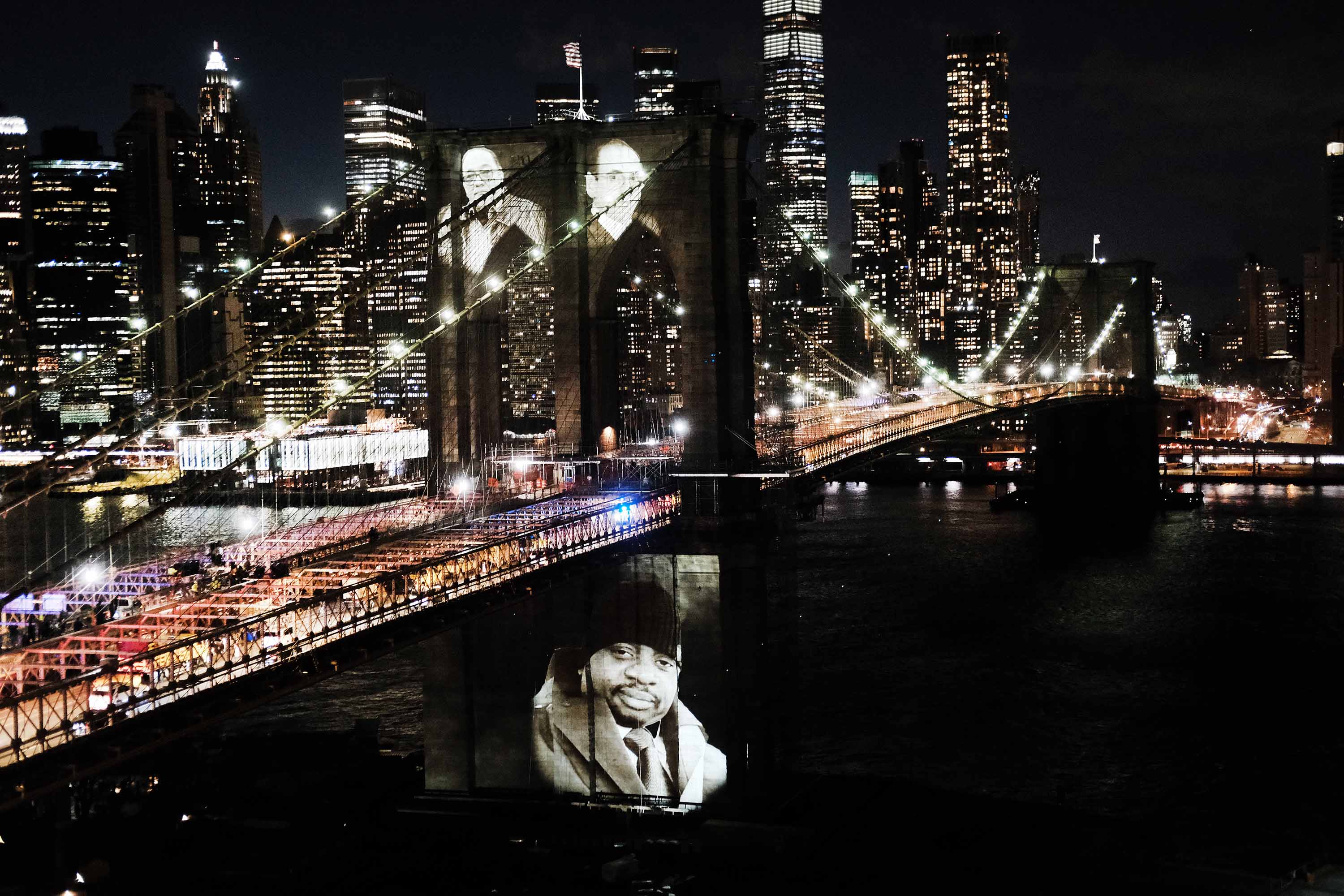 Faces of victims of COVID-19 are projected onto the Brooklyn Bridge during “A COVID-19 Day of Remembrance” memorial service on March 14, in New York City. 