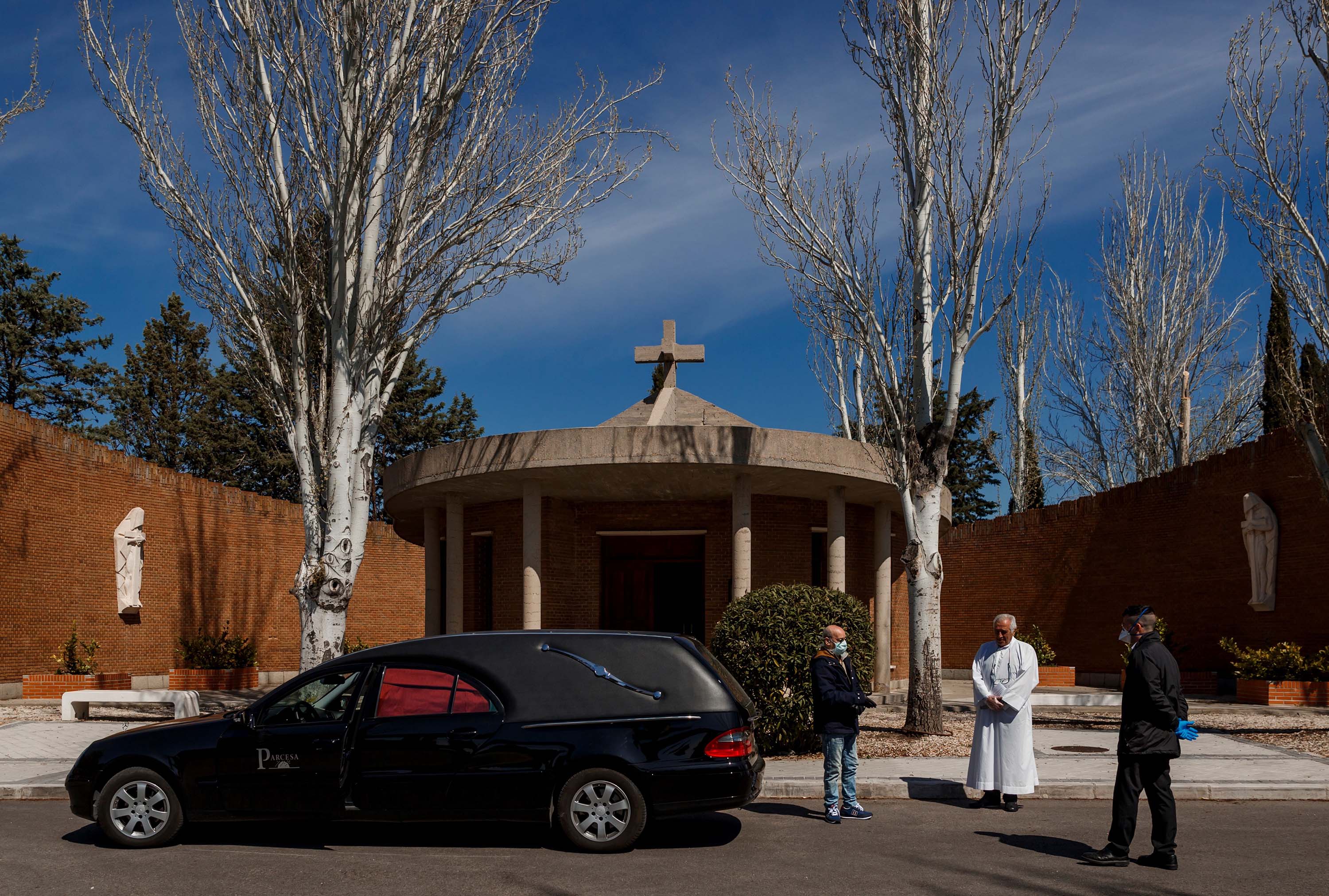 Mortuary employees and a priest stand outside the Fuencarral cemetery in Madrid before the burial of a coronavirus victim on March 29.