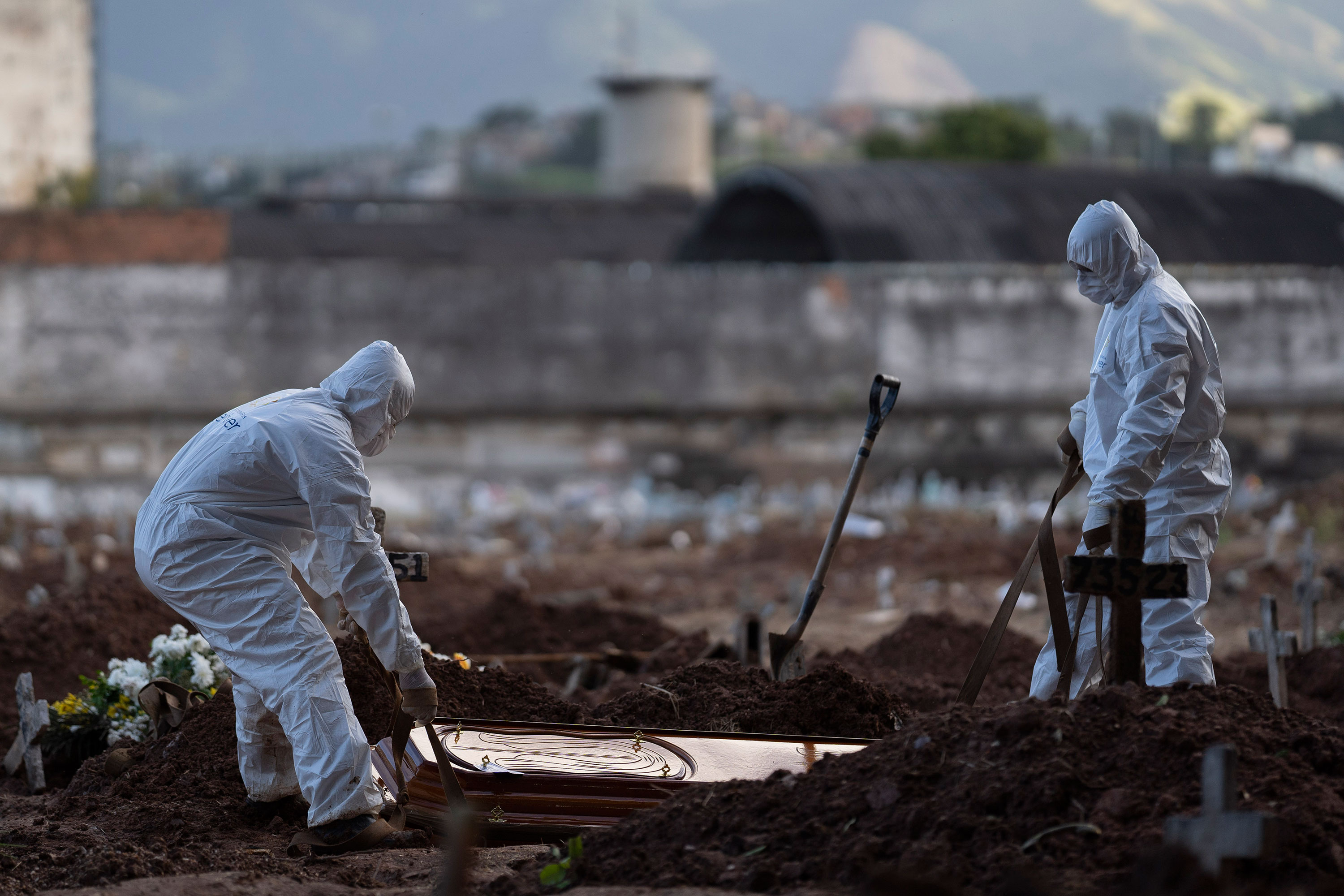 Cemetery workers wearing hazmat suits bury the coffin of a c in Rio de Janeiro, Brazil, Friday, May 8.