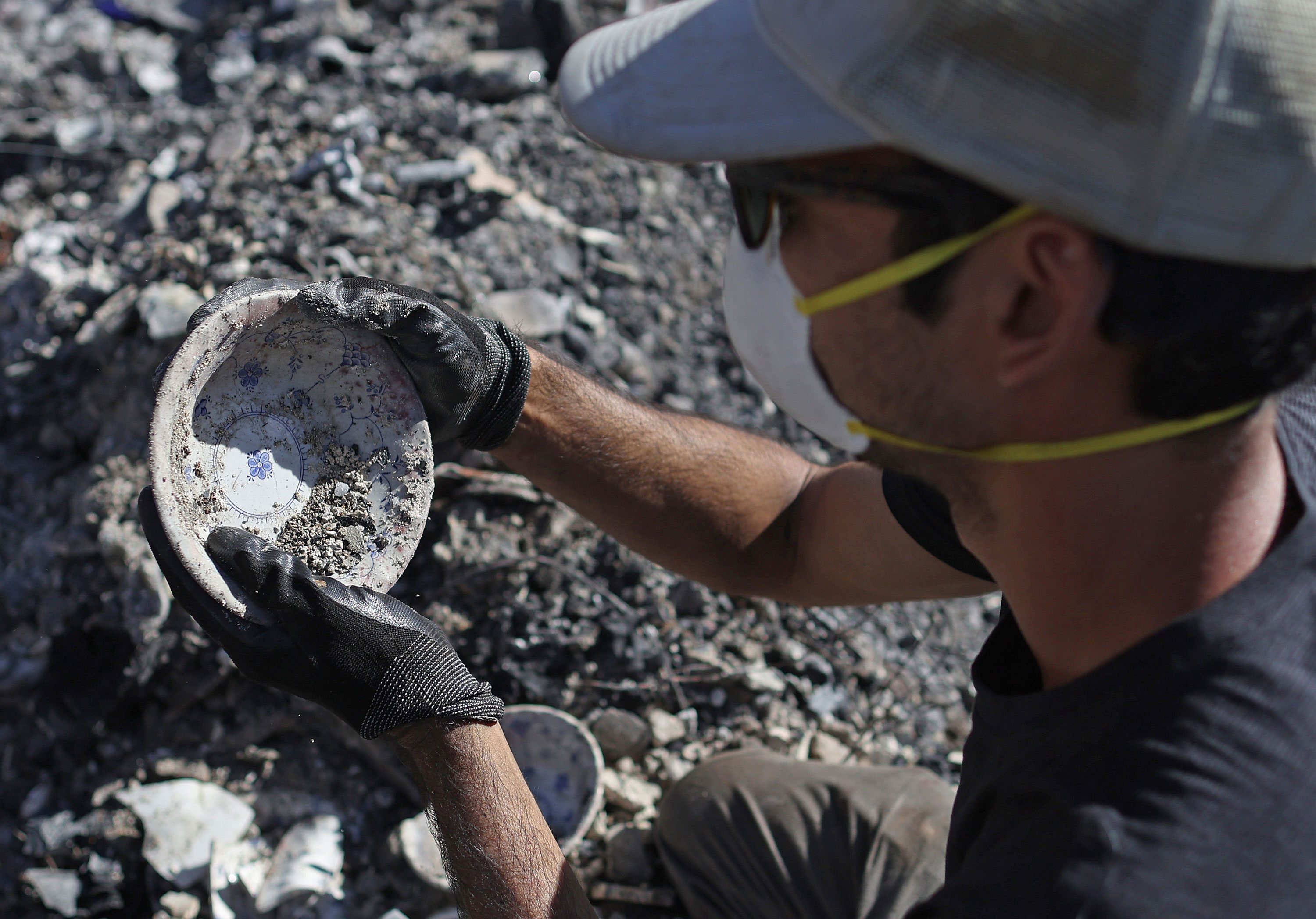 Brook Cretton salvages a bowl he found while sifting through the rubble of a home destroyed by wildfire in Kula, Hawaii, on Saturday. 