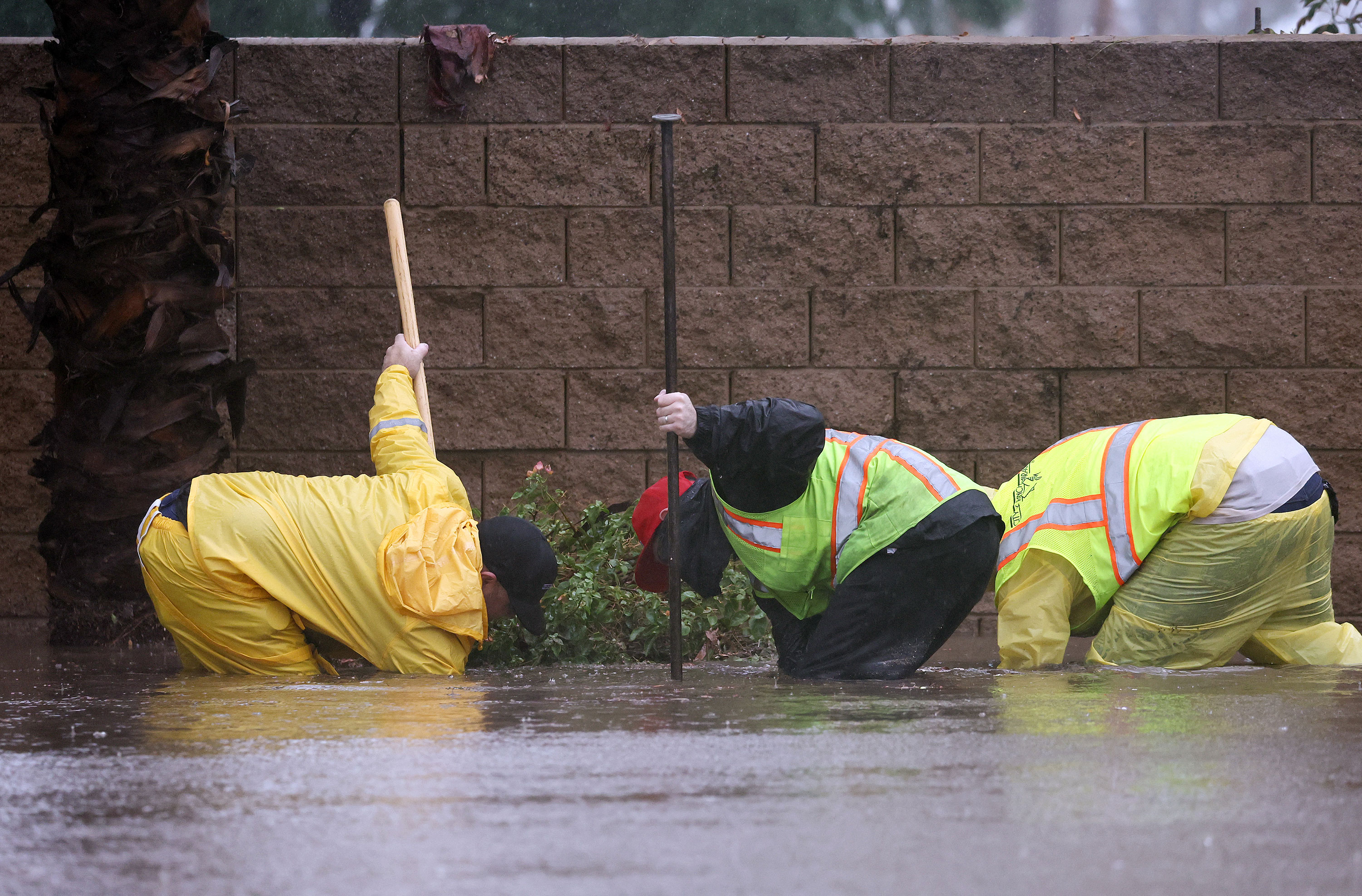 Workers attempt to unclog a drain on a flooded street in Rancho Mirage, California, on Sunday.