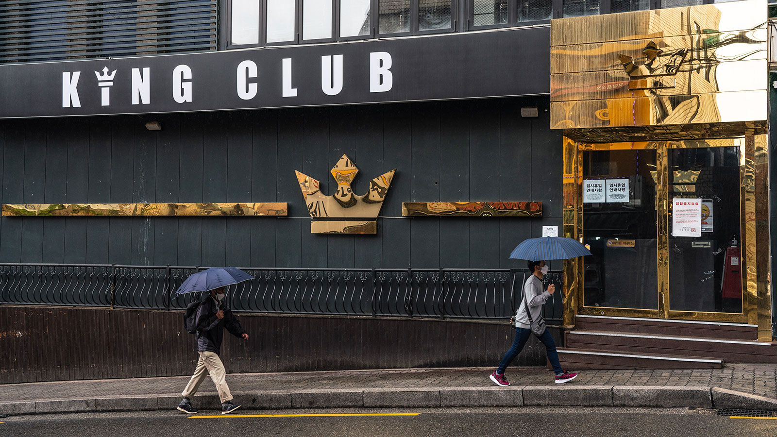 People wearing masks walk by a closed nightclub in the Itaewon district of Seoul.