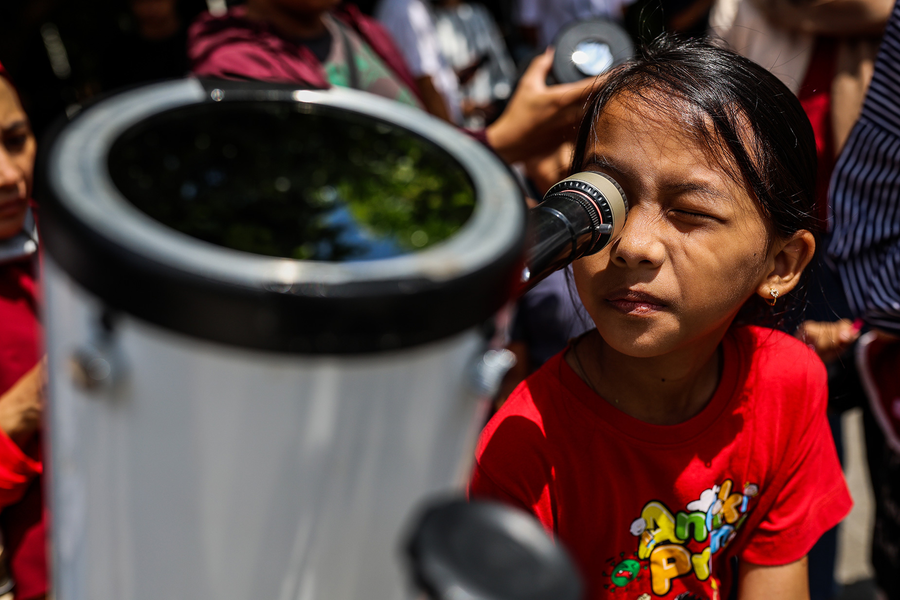 A girl uses a telescope to observe a partial solar eclipse in Yogyakarta, Indonesia, on April 20, 2023. 