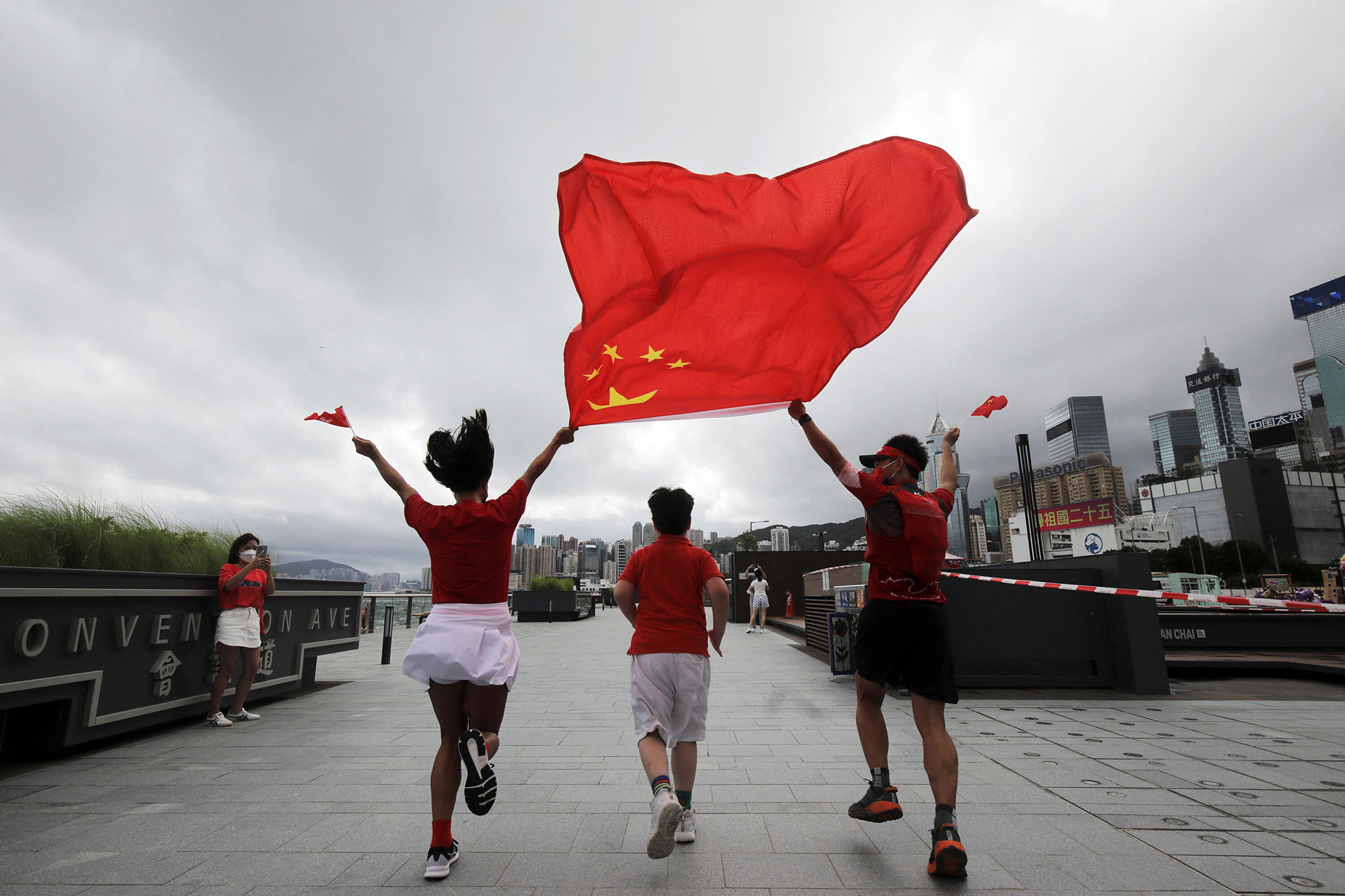 支持者たちは、7月1日に香港で開催された旧英国植民地の中国統治への引き継ぎから25周年を迎えるコンベンションアベニューで、中国と香港の旗を掲げてポーズをとります。