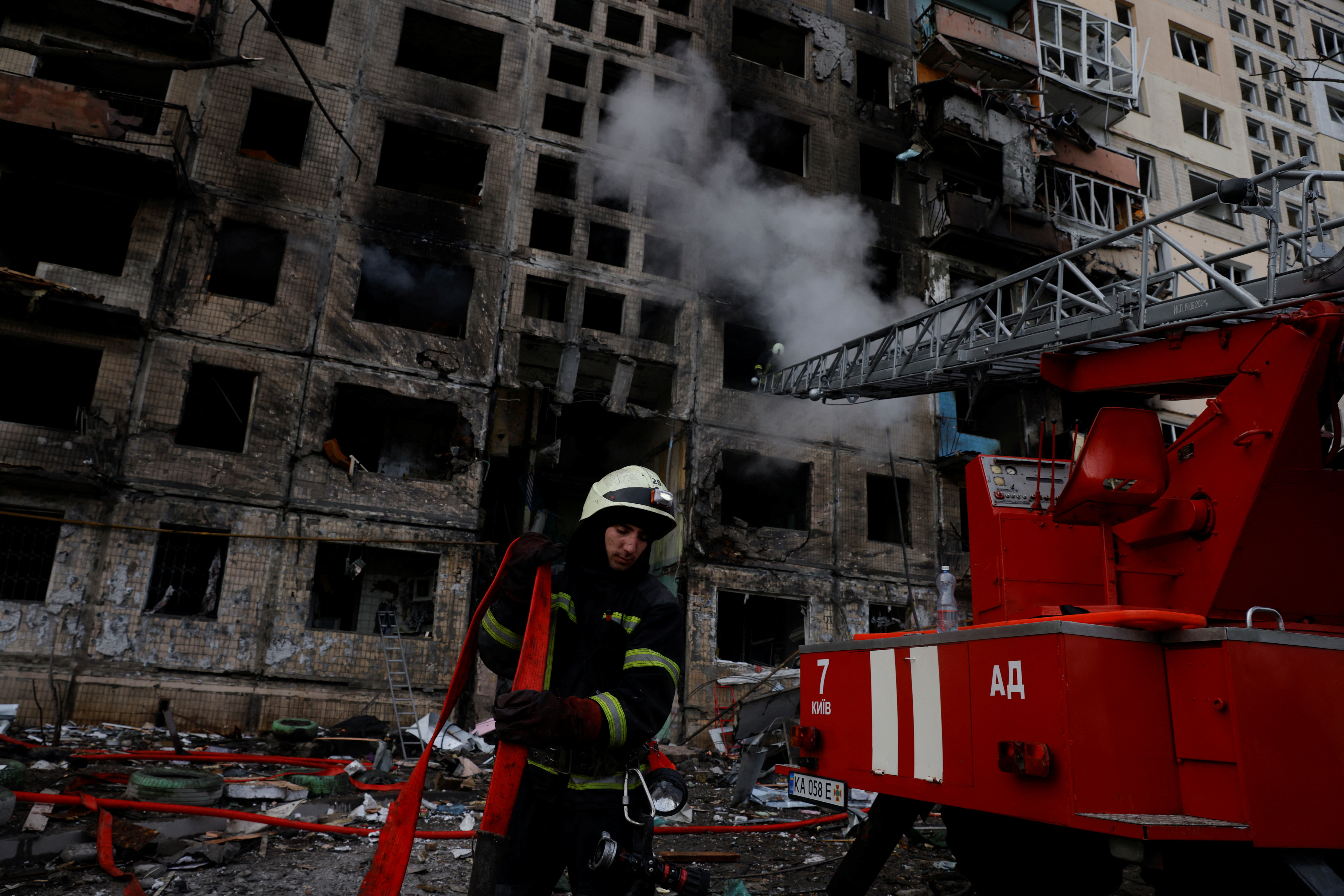 A firefighter carries a hose in front of a residential building that was hit by a shell in the Obolon district in Kyiv, Ukraine, on March 14.