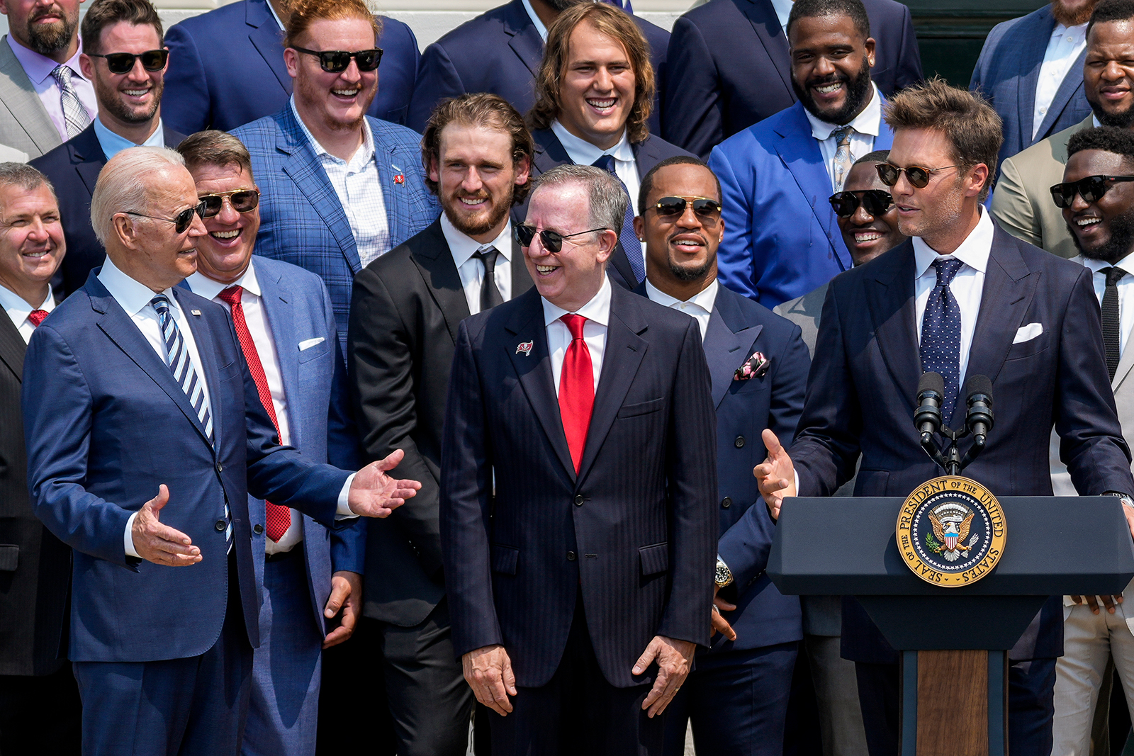 President Joe Biden laughs as quarterback Tom Brady jokes while speaking as the 2021 NFL Super Bowl champion Tampa Bay Buccaneers are welcomed to the South Lawn of the White House on July 20, 2021 in Washington, DC.