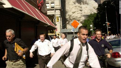 In this Sept. 11, 2001, file photo, people run from the collapse of one of the twin towers at the World Trade Center in New York. Stephen Cooper, far left, fleeing smoke and debris as the south tower crumbled just a block away on Sept. 11, has died from coronavirus, his family said, according to The Palm Beach Post.