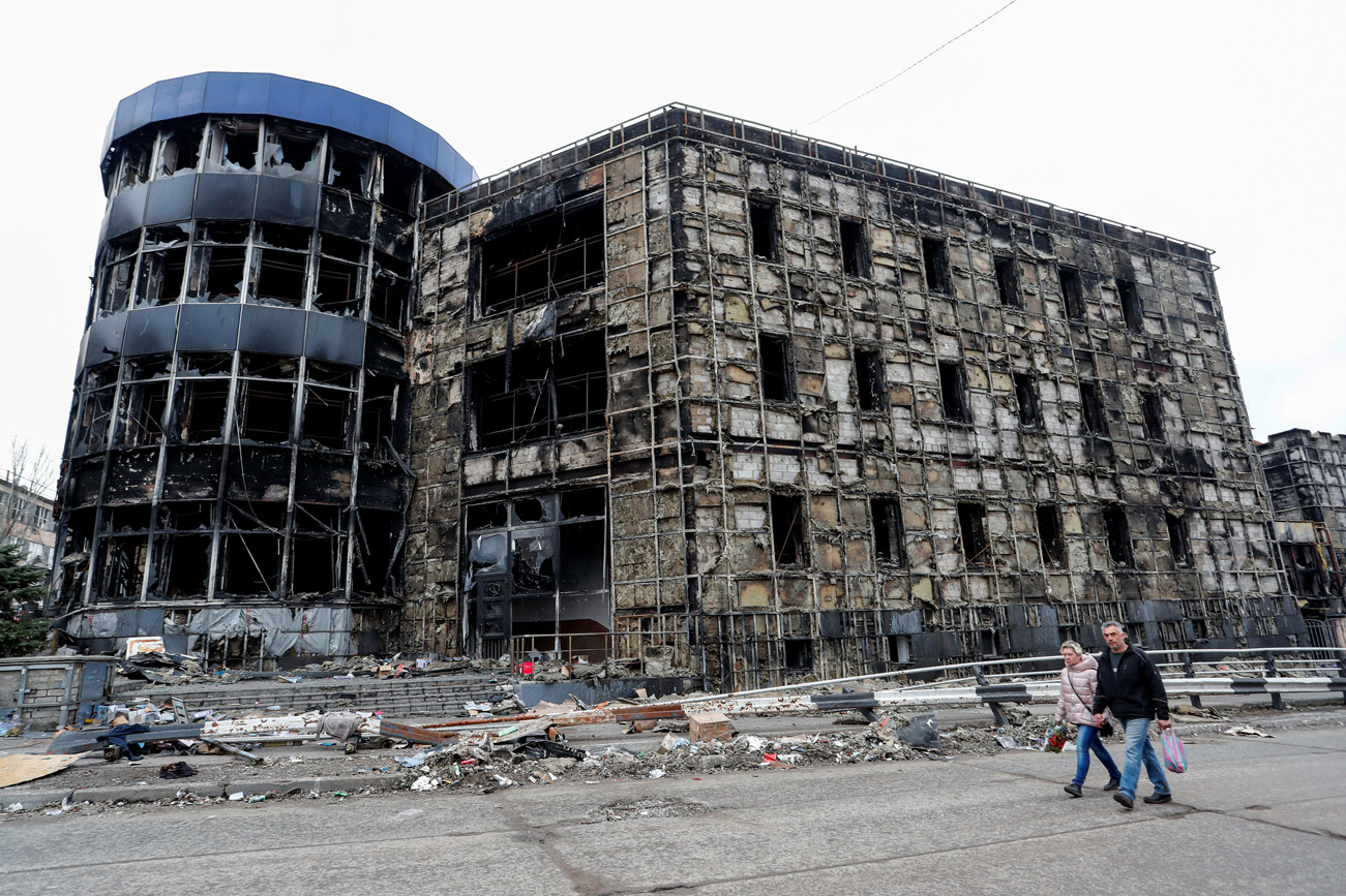 People walk past a destroyed building in Mariupol on April 14.