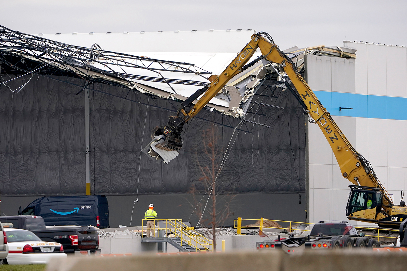 Workers use equipment to remove a section of roof left on a heavily damaged Amazon fulfillment center Saturday, Dec. 11, 2021, in Edwardsville, Ill. (Jeff Roberson/AP)