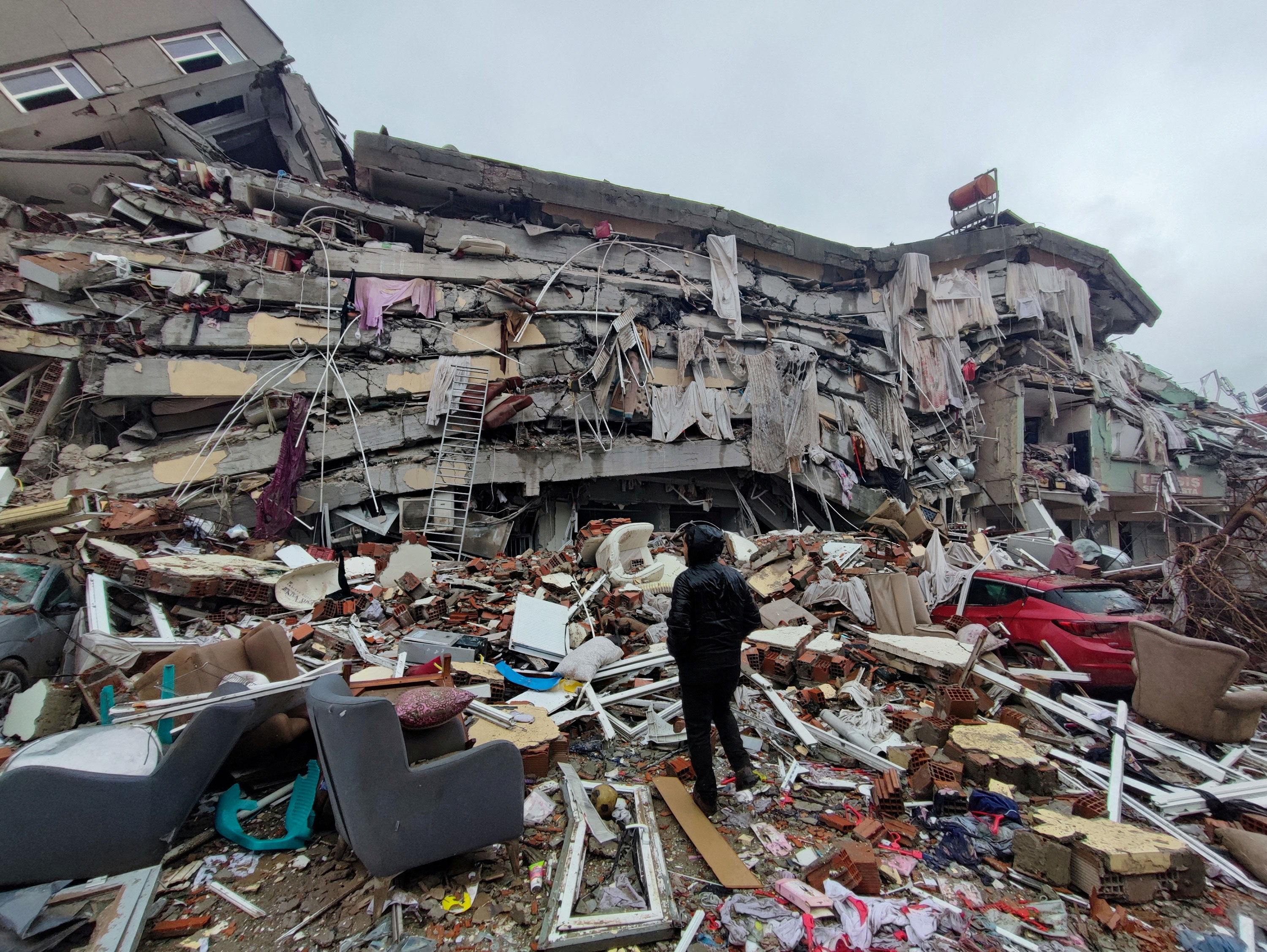 A man stands in front of collapsed buildings in Kahramanmaras, Turkey, on Monday.
