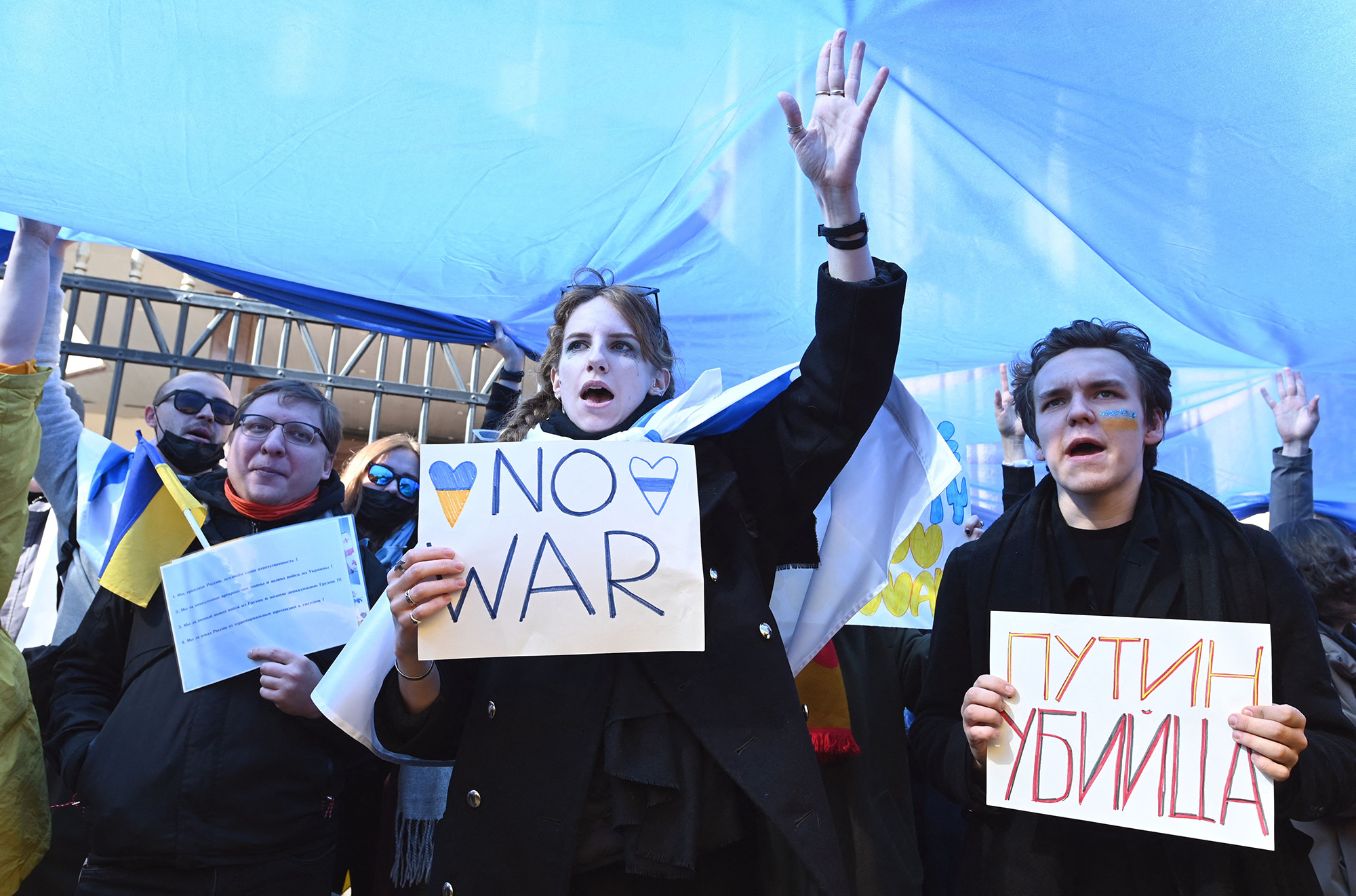 Protesters hold signs under a giant flag during a rally in front of the former Russian embassy, in Tbilisi, Georgia, on March 12, to protest against the Russian invasion of Ukraine.
