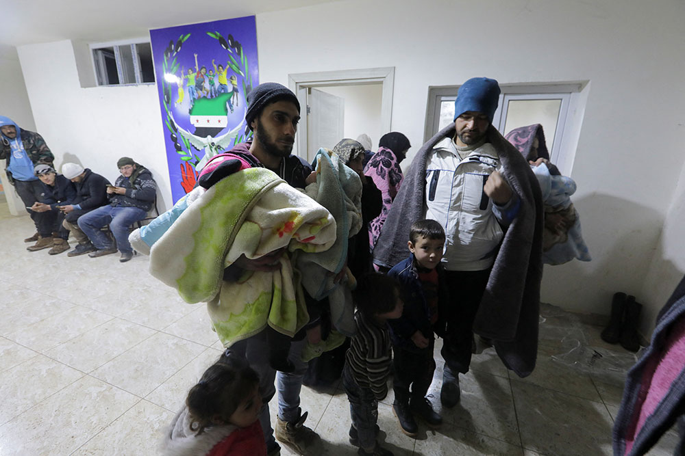 People arrive at a temporary shelter inside a sports center in A'zaz, Syria.