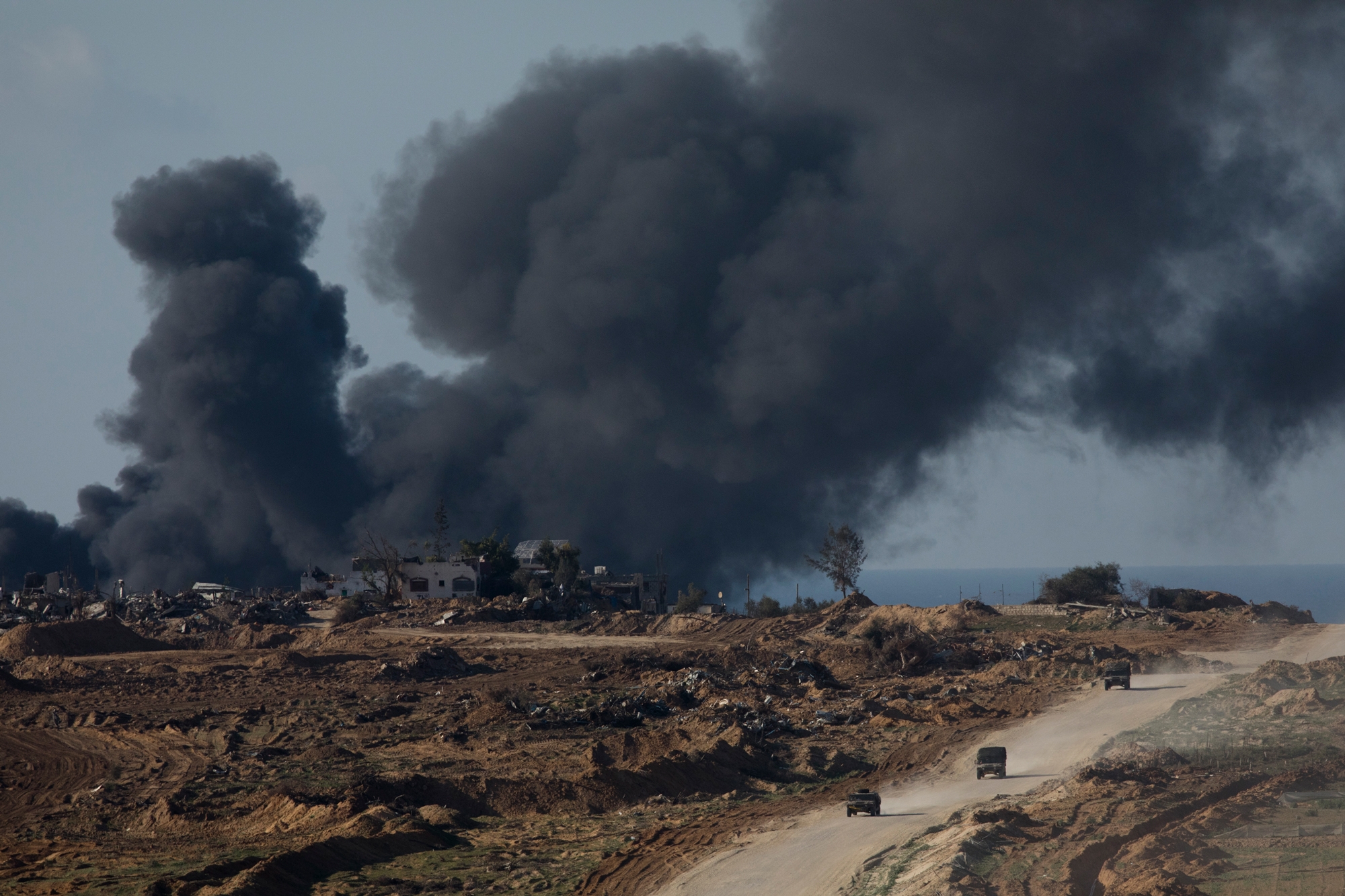 Israeli troops move out of Gaza as smoke rises during Israeli bombardment as seen from the Israeli side of the border on January 5, in southern Israel.