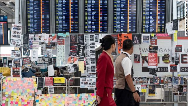 Flight attendants walk past a display board covered with memos and posters at Hong Kong's international airport on Tuesday.