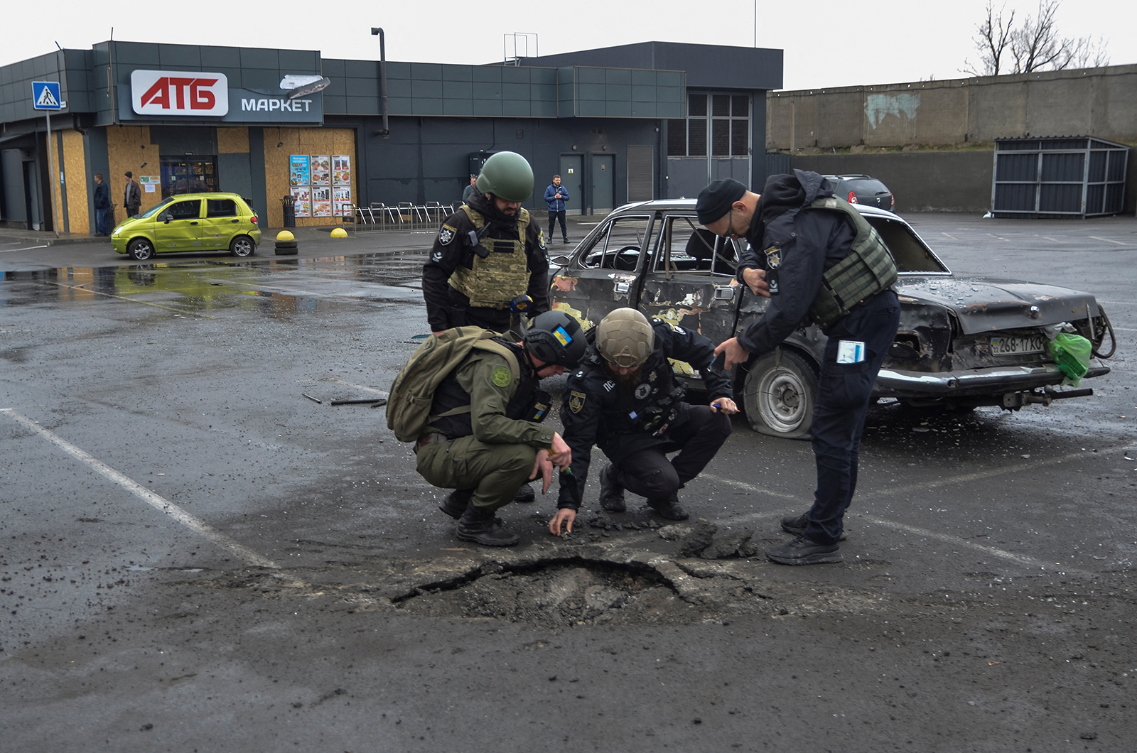 Police investigators inspect a shell crater left by a Russian military strike in Kherson, Ukraine, on March 11. 