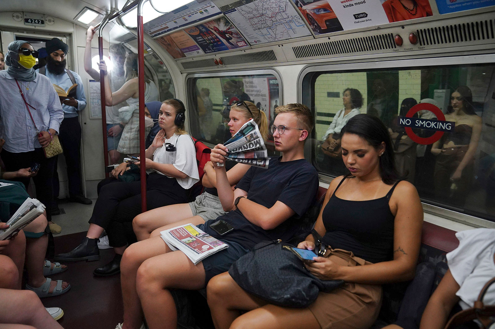 A man fans himself with a newspaper to keep himself cool while traveling on London's Underground on Monday.