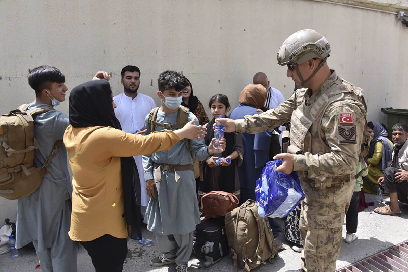 A Turkish soldier distributes water to Turkish nationals waiting to evacuate the airport in Kabul on August 18. 