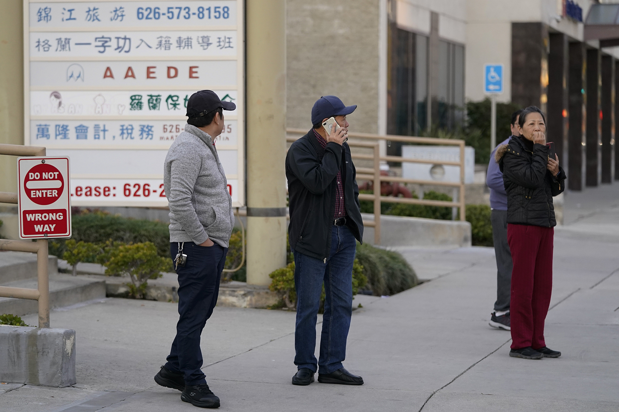 Several residents survey the scene near a ballroom dance club in Monterey Park, California on Sunday.