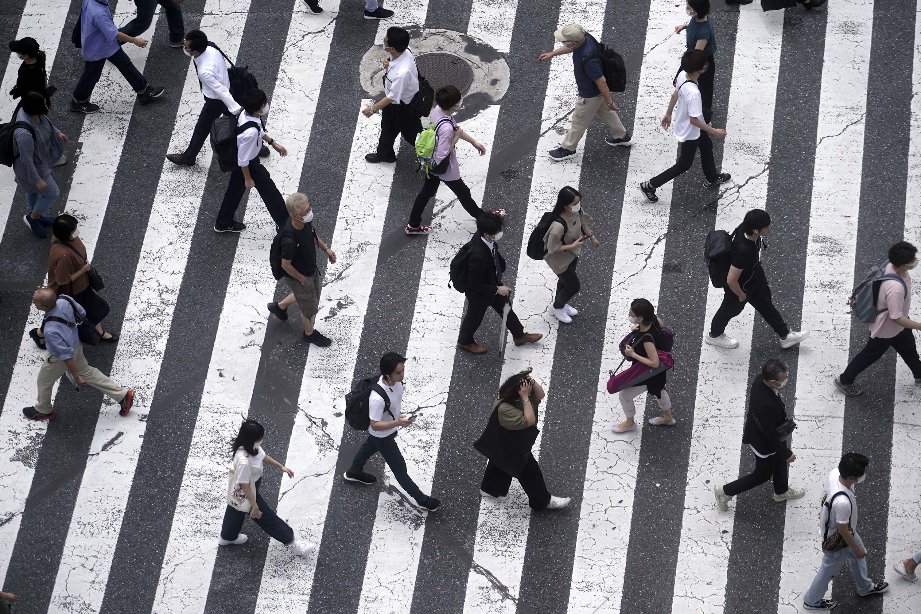 People walk across Tokyo's Shibuya pedestrian crossing on Tuesday.