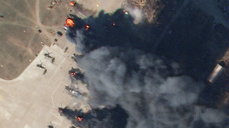 Na zvětšené části obrázku jsou vidět hořící vrtulníky. 