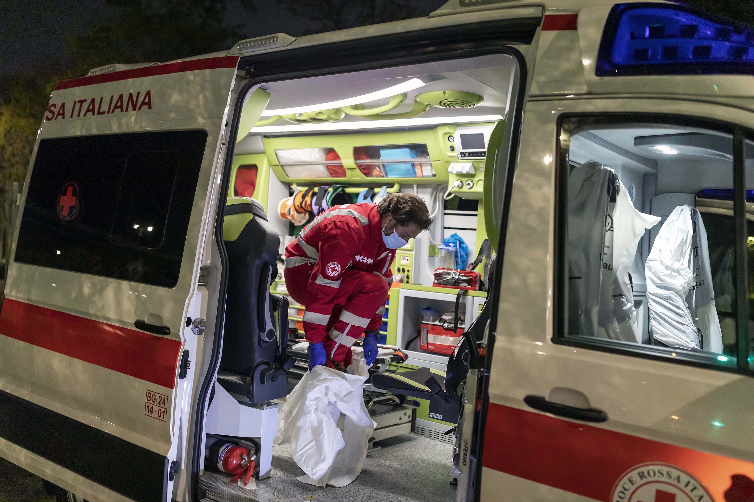 Marco Vangelista, membru al echipei de ambulanță a Crucii Roșii italiene, pune echipament de protecție în timp ce răspunde la urgența unui pacient cu coronavirus 8 aprilie la Bergamo, Italia.