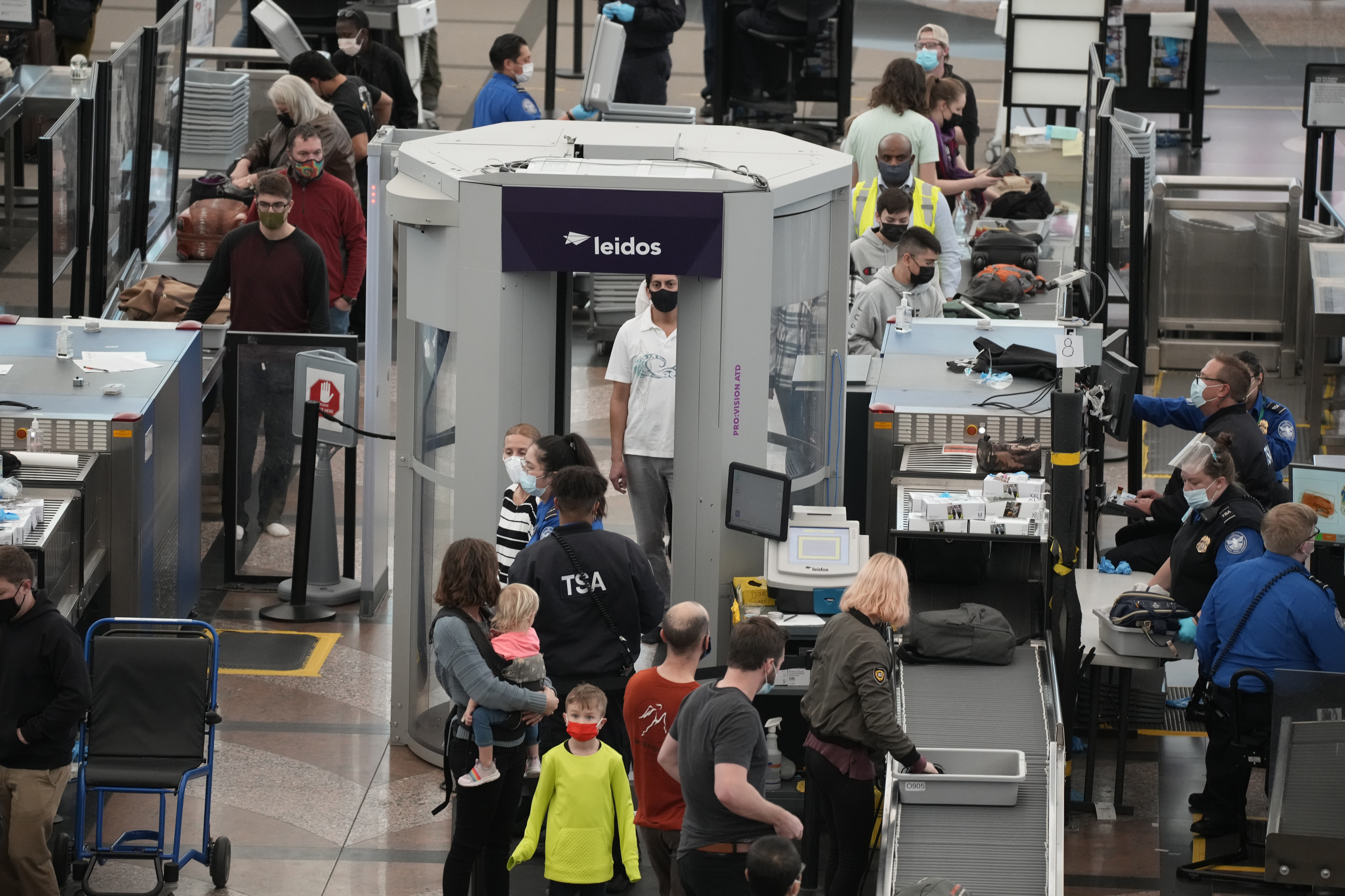 Travellers go through the south security checkpoint in the terminal of Denver International Airport Friday, Dec. 24, 2021, in Denver.