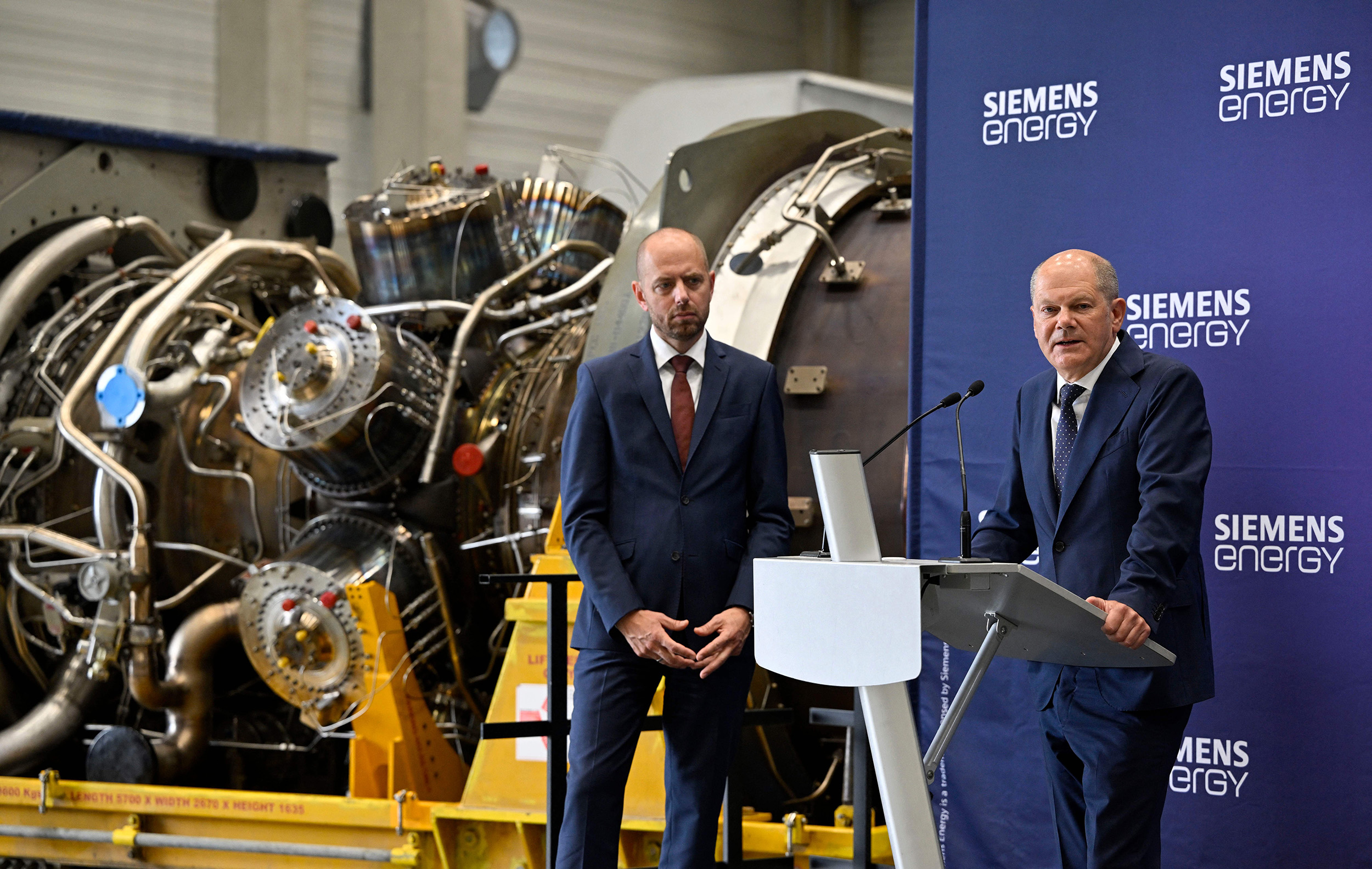 German Chancellor Olaf Scholz, right, stands next to Christian Bruch, President and CEO of Siemens Energy in front of a turbine for the Nord Stream 1 pipeline at the plant of Siemens Energy in Muelheim an der Ruhr, Germany, on August 3.
