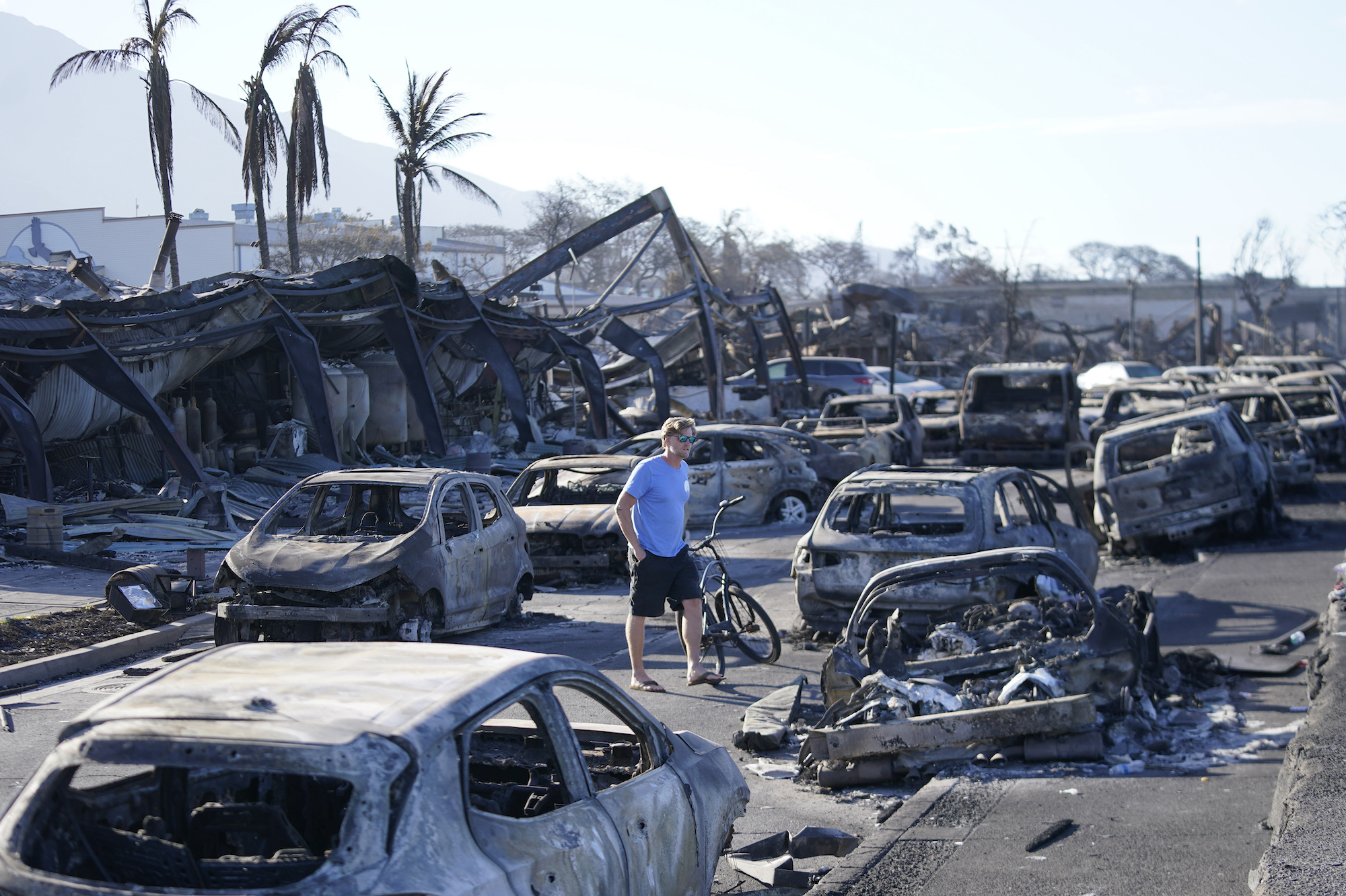 A man walks through wildfire damage on Friday in Lahaina.
