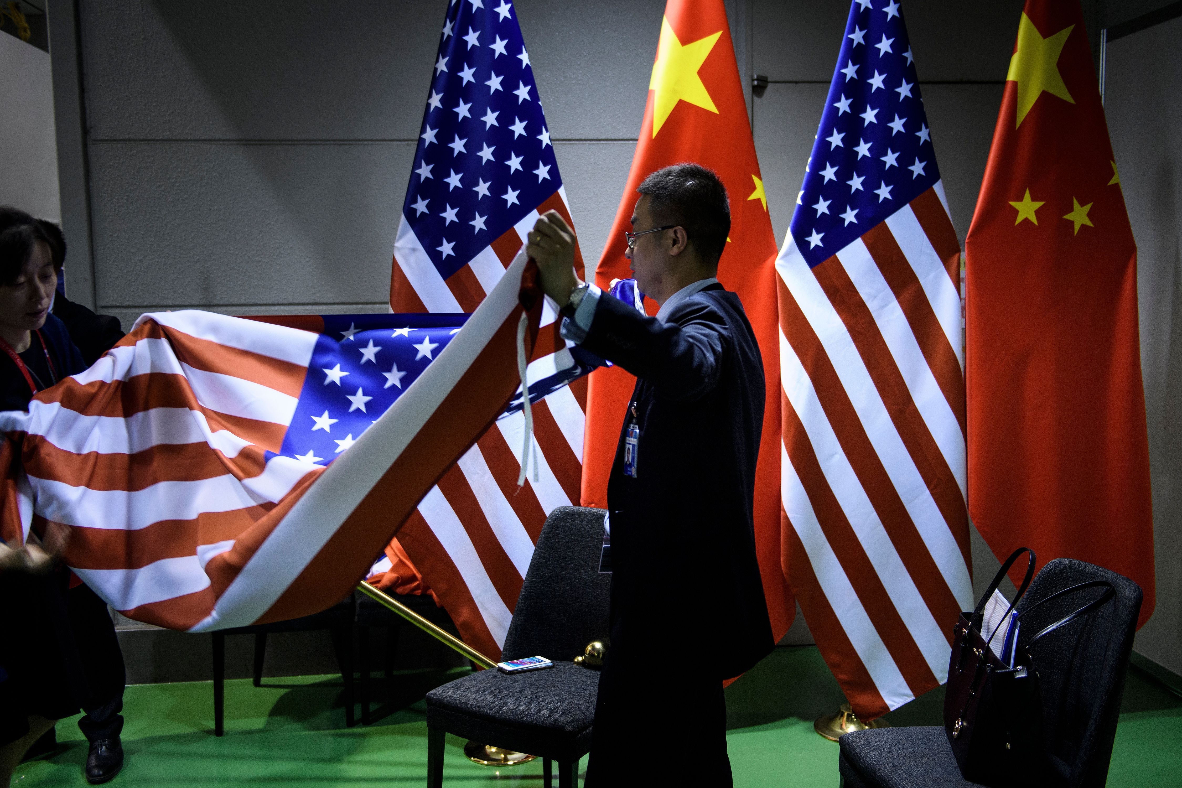 Staff fold flags while US President Donald Trump and China's President Xi Jinping hold a bilateral meeting on the sidelines of the G20 Summit in Osaka on June 29.
